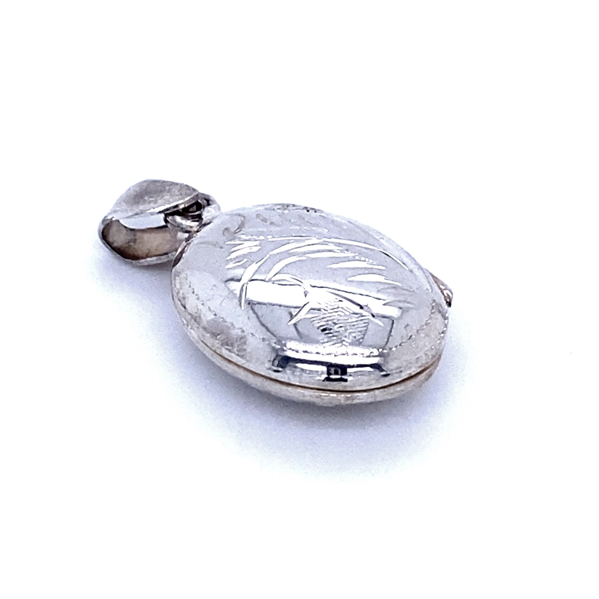 A close-up image of a sterling silver pendant in the form of an Oval Locket with Plant Etching. The Victorian locket features a hinged lid and a small attached loop for a chain.