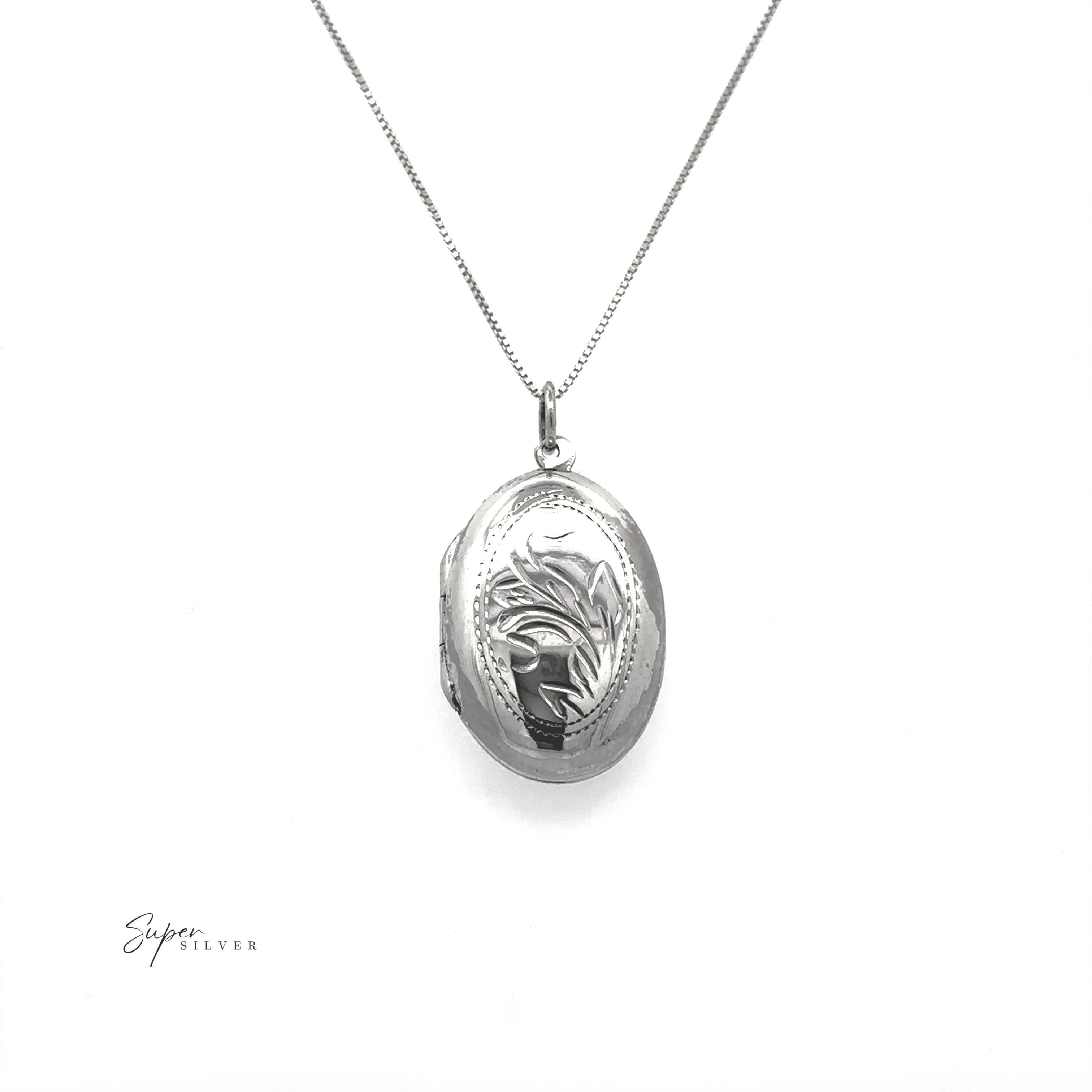 The Oval Silver Locket with Leaf Design features an engraved pendant on a fine chain, perfect as a photo keepsake and showcased on a white background.