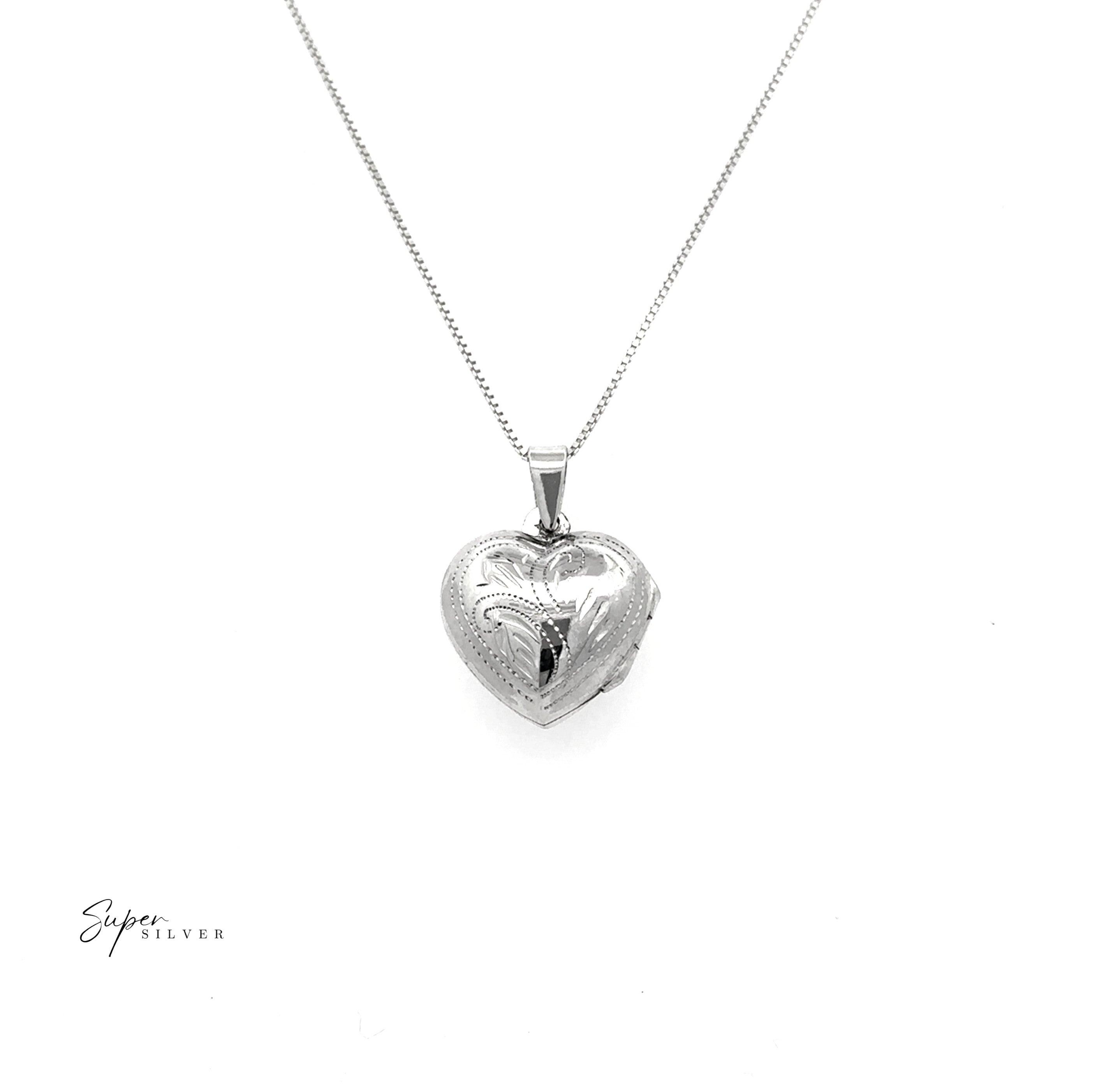 A Tiny Heart-Shaped Locket with filigree etching hangs from a slender silver chain, displayed on a white background.