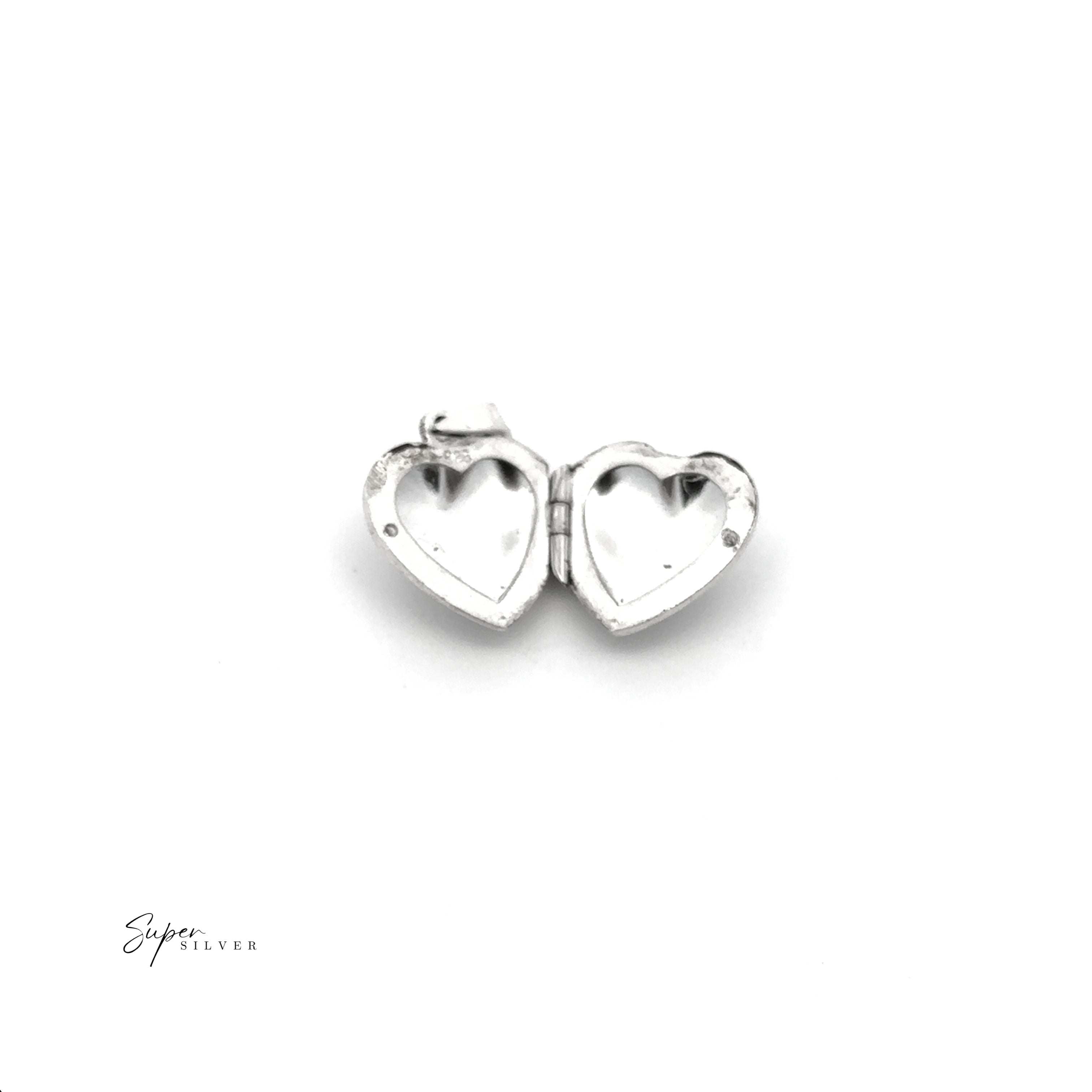 A Tiny Heart-Shaped Locket with Filigree Etching in sterling silver is open to show two empty compartments, set against a white background with "Super Silver" text in the corner.