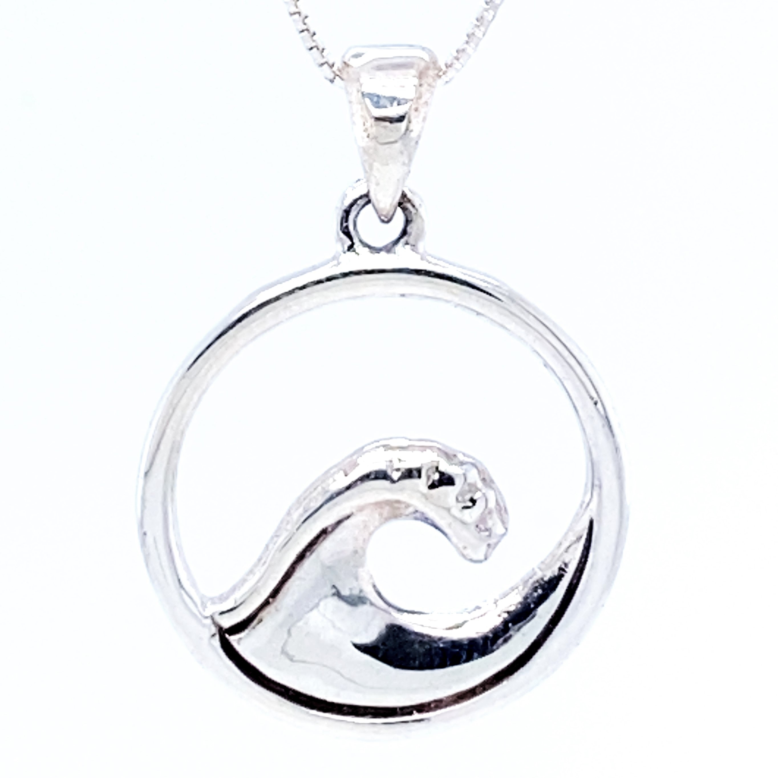 A Serene Wave Pendant set within a circular frame, hanging from a chain, exudes beachy vibes.