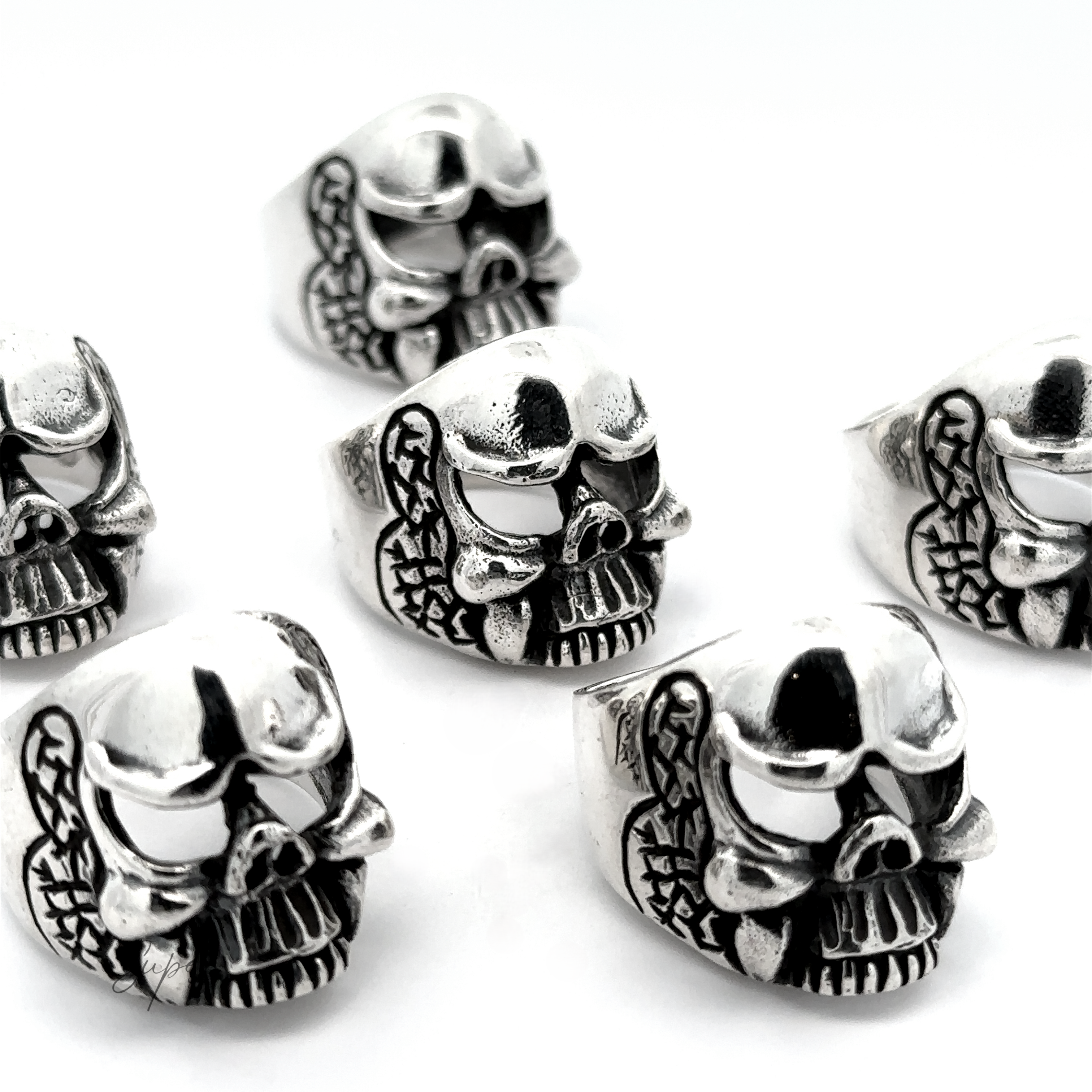 Six Skull Statement Rings with snake details, arranged on a white background, showcase an edgy style. Made from .925 Sterling Silver, these intricate pieces are perfect for adding a rebellious touch to any outfit.