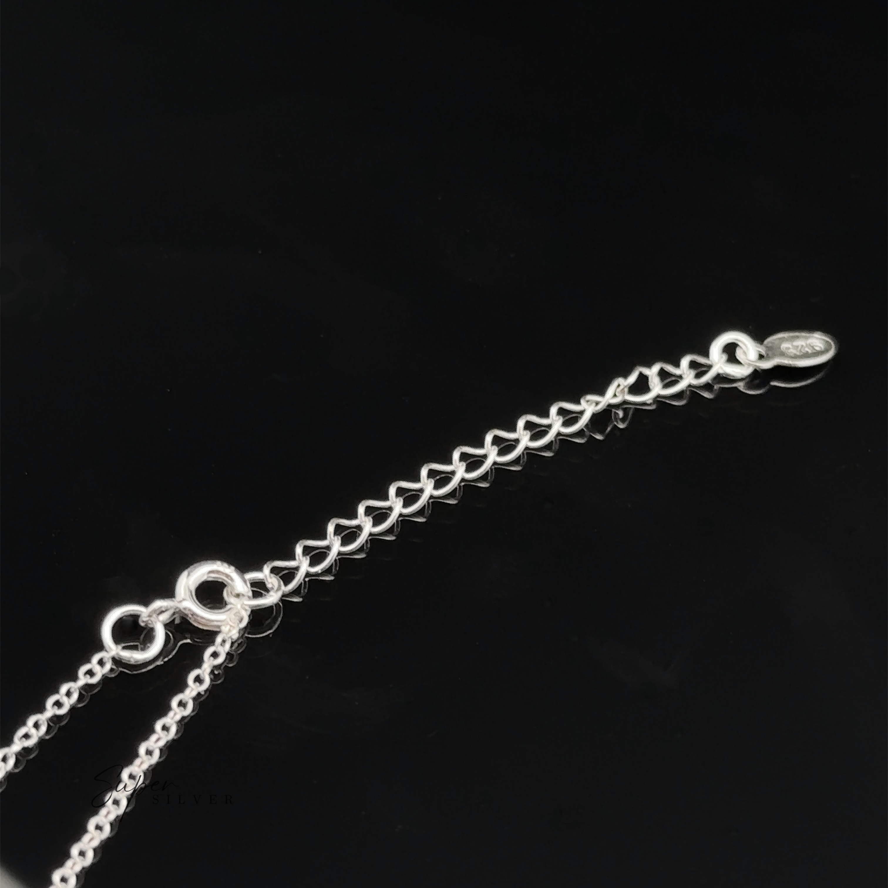 A close-up of the Silver Open Heart Charm Necklace, adorned with delicate open heart charms and an adjustable clasp, set against a black background.
