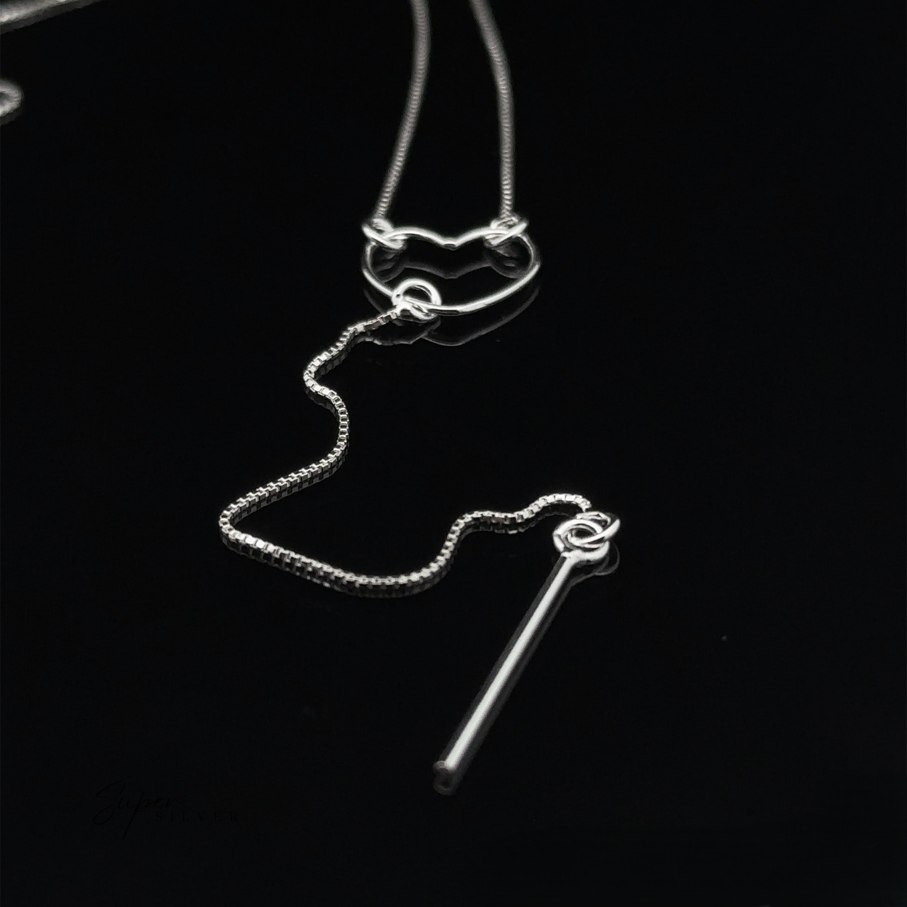 A stunning Open Heart Lariat Necklace, crafted from sterling silver, features a heart and bar pendant displayed elegantly against a black background.
