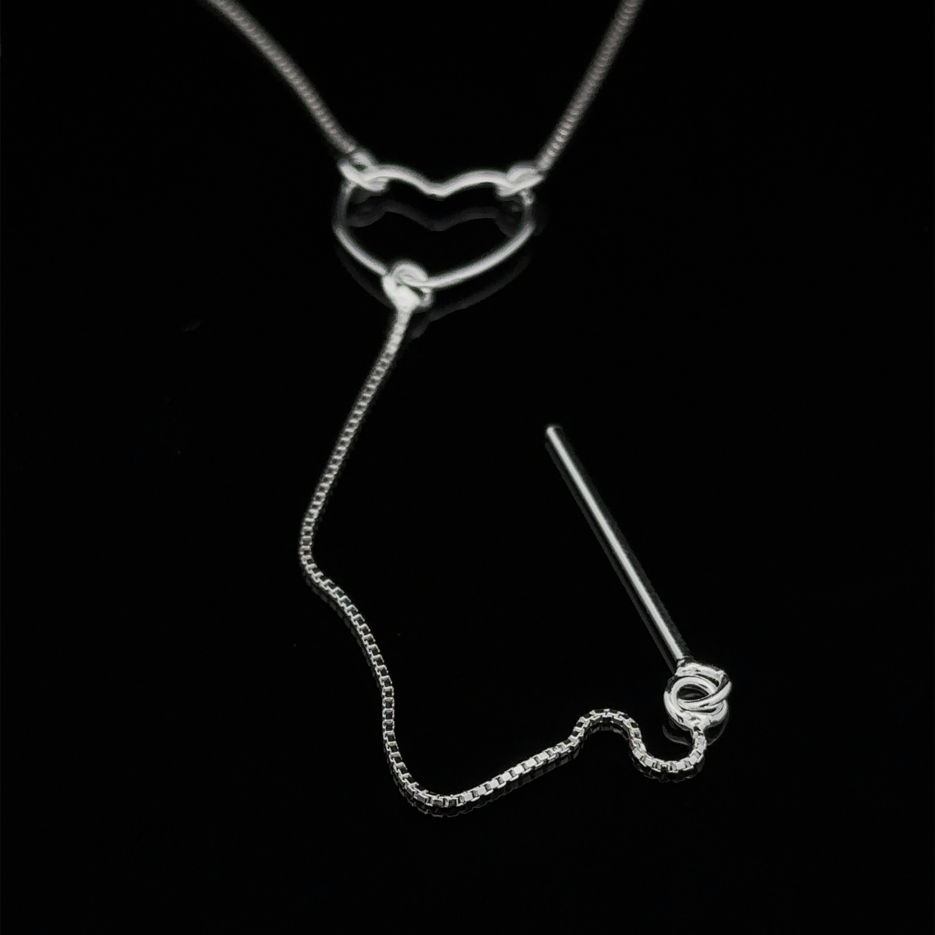 A delicate Open Heart Lariat Necklace featuring a heart-shaped pendant and a thin chain, displayed on a black background.