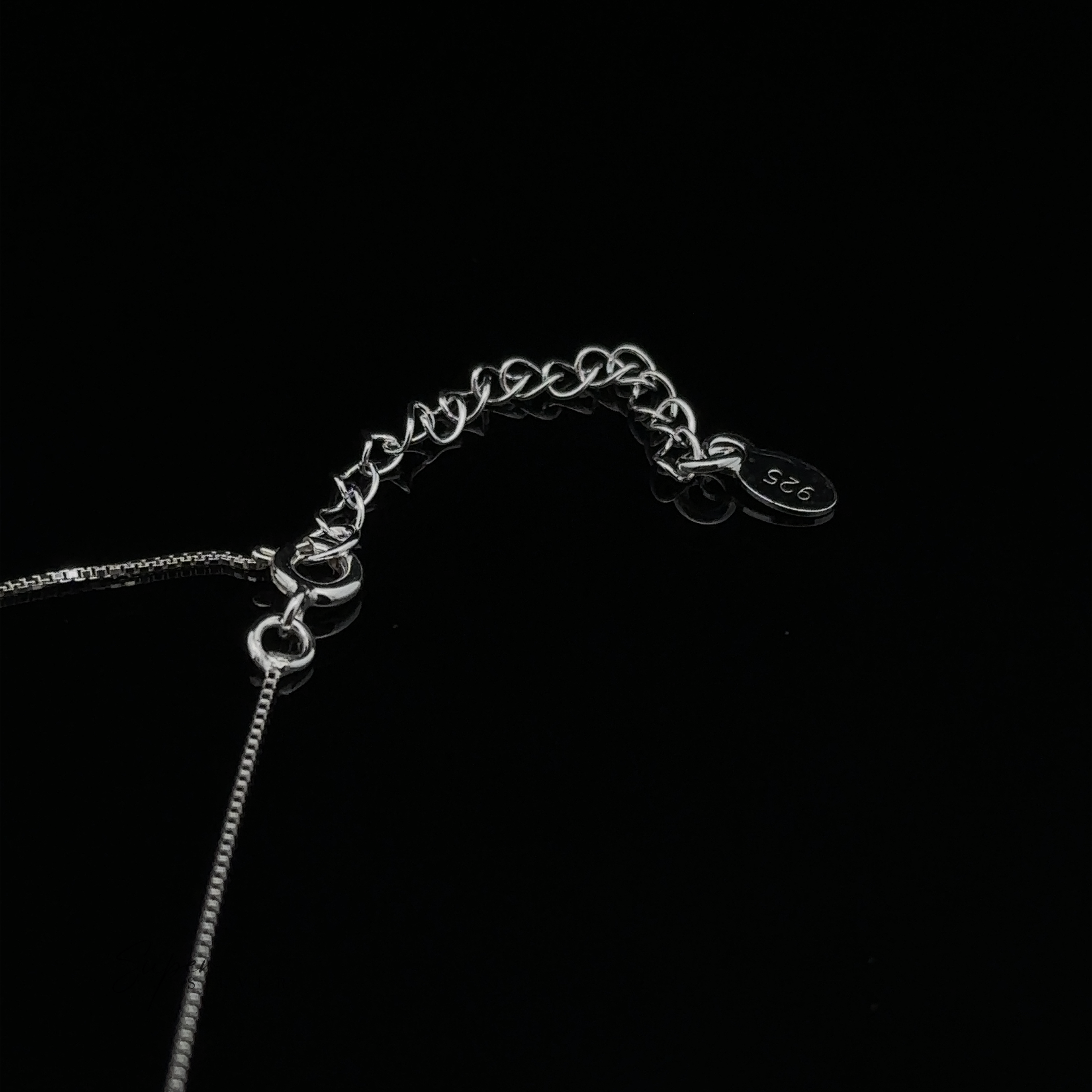 Close-up of a dainty sterling silver Open Heart Lariat Necklace clasp on a black background with a small tag engraved "925.