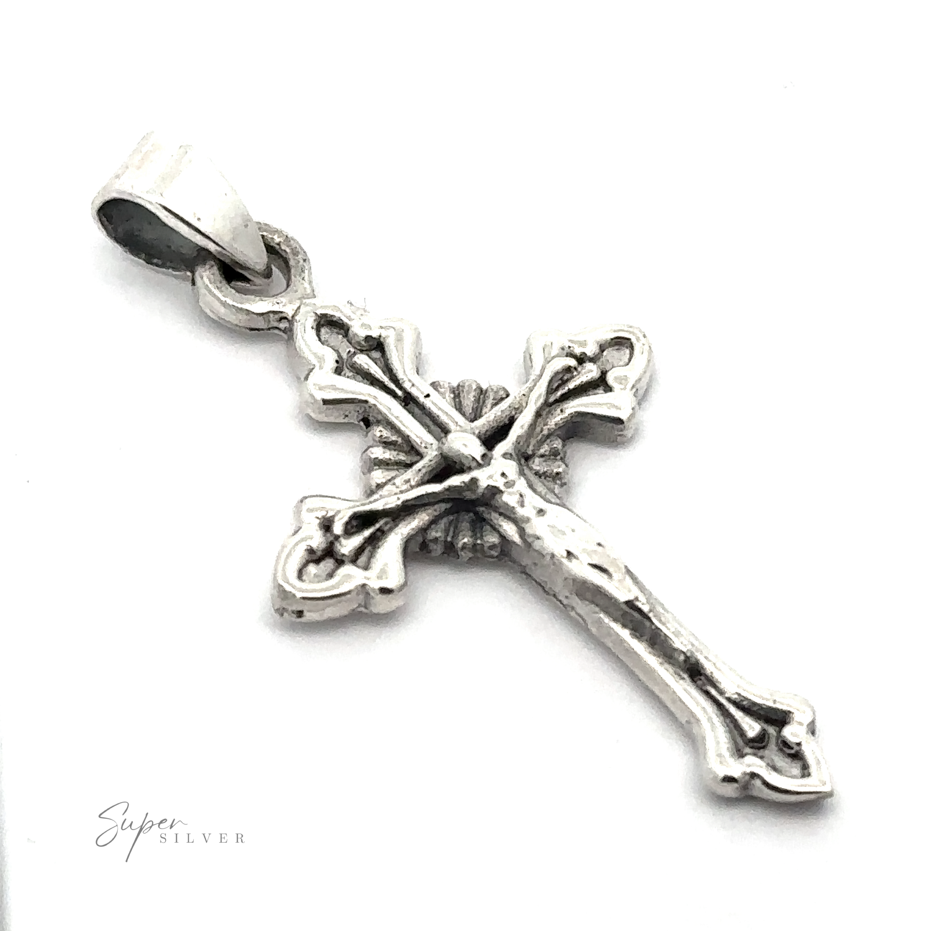 Close-up of a detailed Crucifix Charm with an ornate design and a bail for attaching to a chain. Little text at the bottom reads "Super Silver".