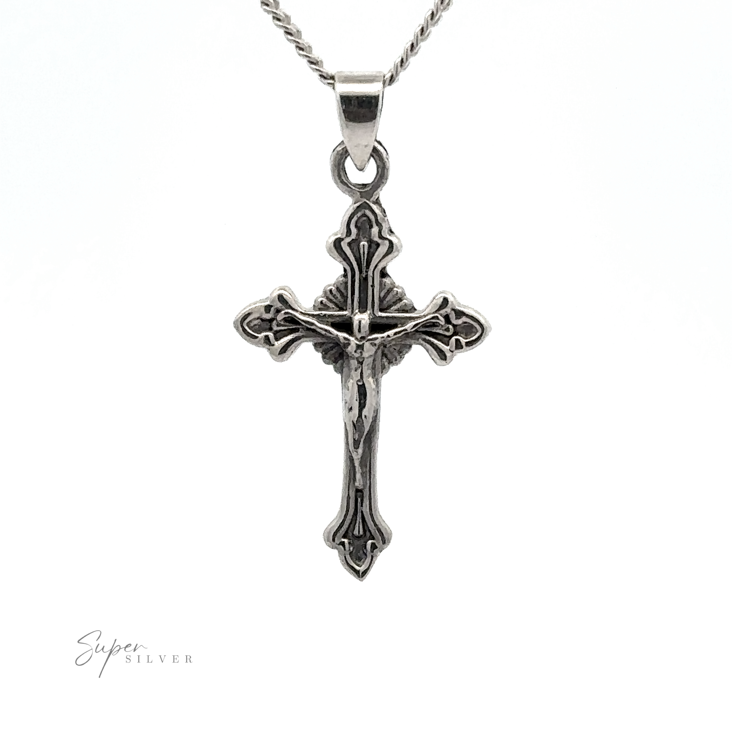 A detailed Crucifix Charm on a chain, with intricate designs and a figure in the center. The background is plain white.