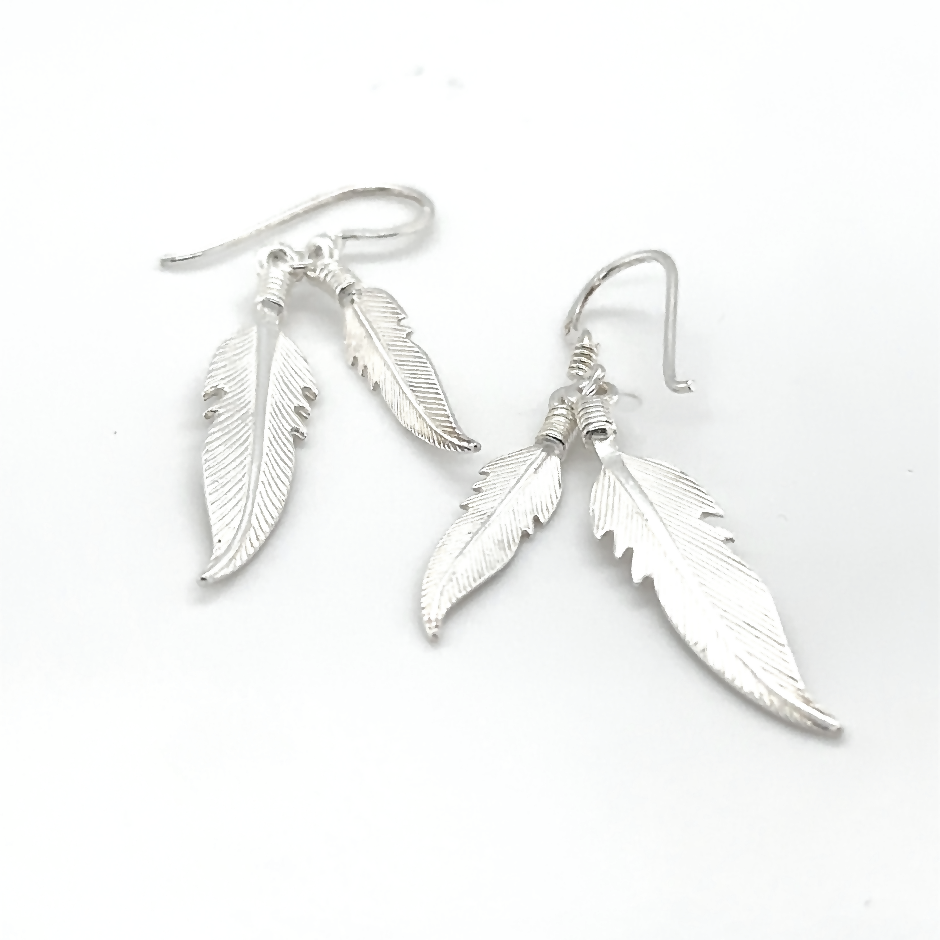A pair of Super Silver Double Feather Earrings on a white background.