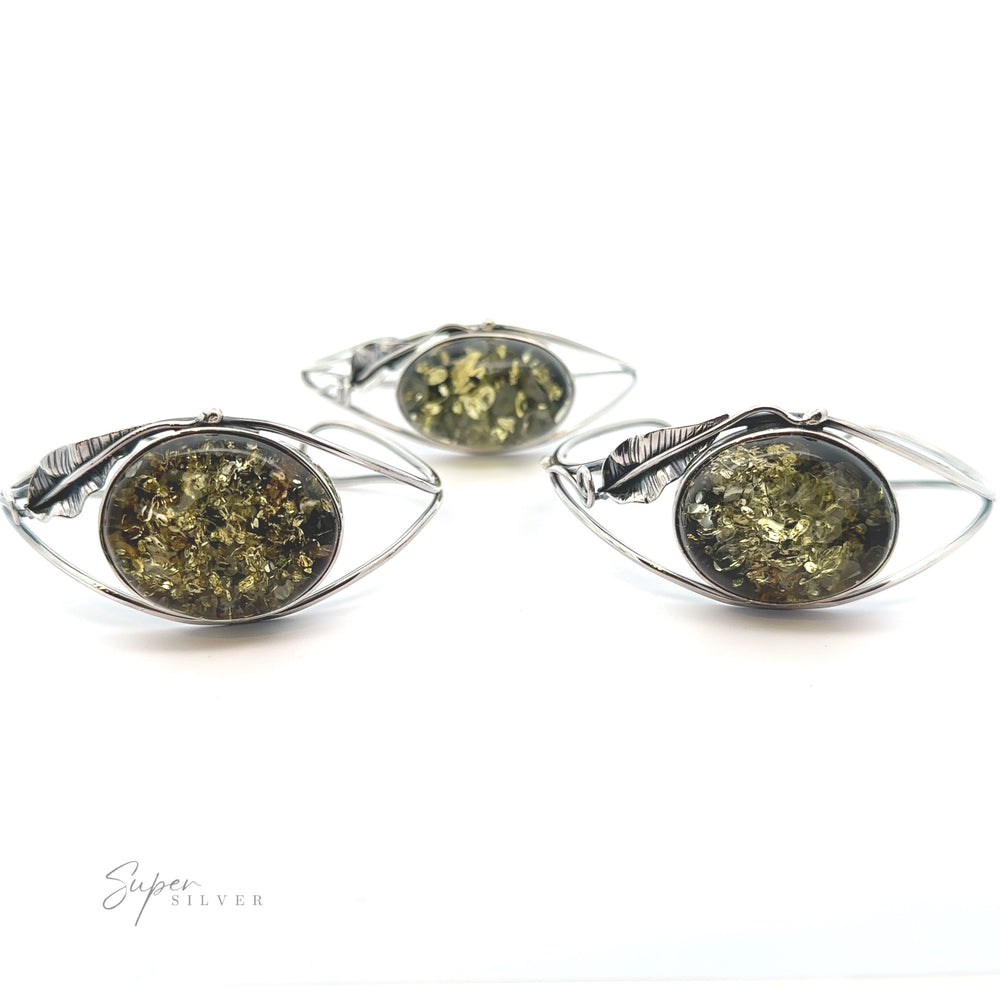 
                  
                    A pair of Delicate Floral Amber Cuff earrings with a green stone in the middle, making a statement.
                  
                