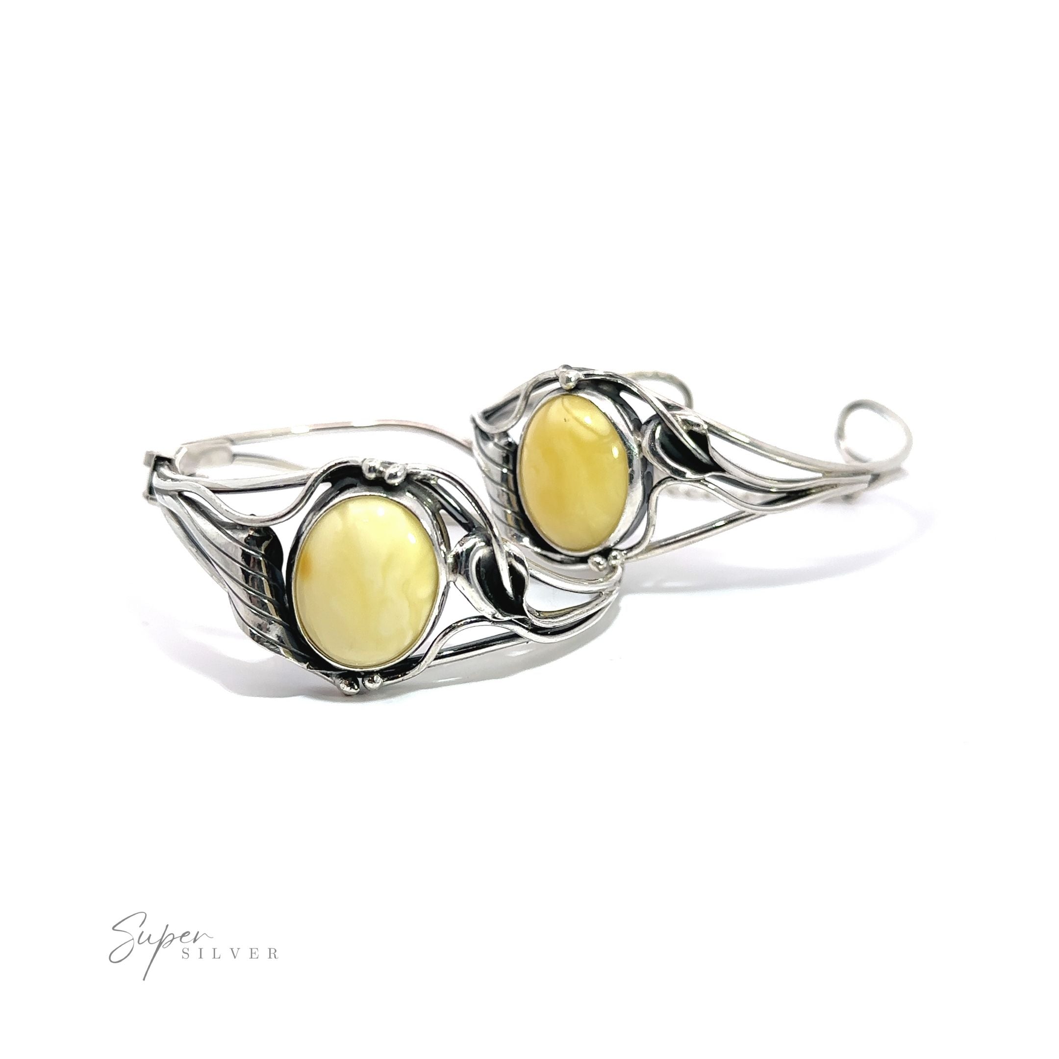 A pair of silver hoop earrings adorned with a Butterscotch Amber Bracelet with Nature Detailing, reminiscent of vintage charm.