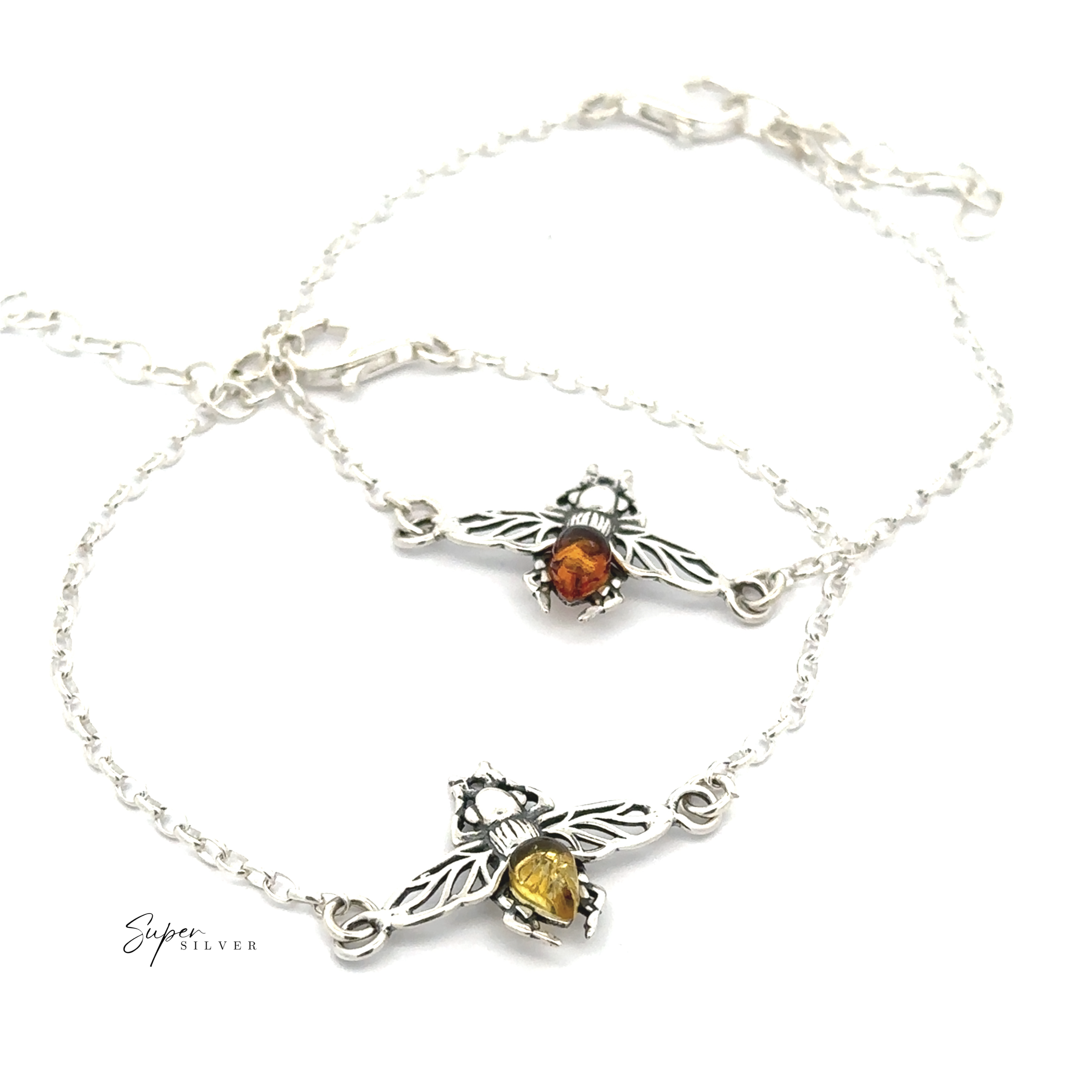 The Baltic Amber Bee Bracelet set features two sterling silver chain bracelets with bee-shaped charms, each adorned with Baltic amber and yellow stones in the center, displayed on a white background.
