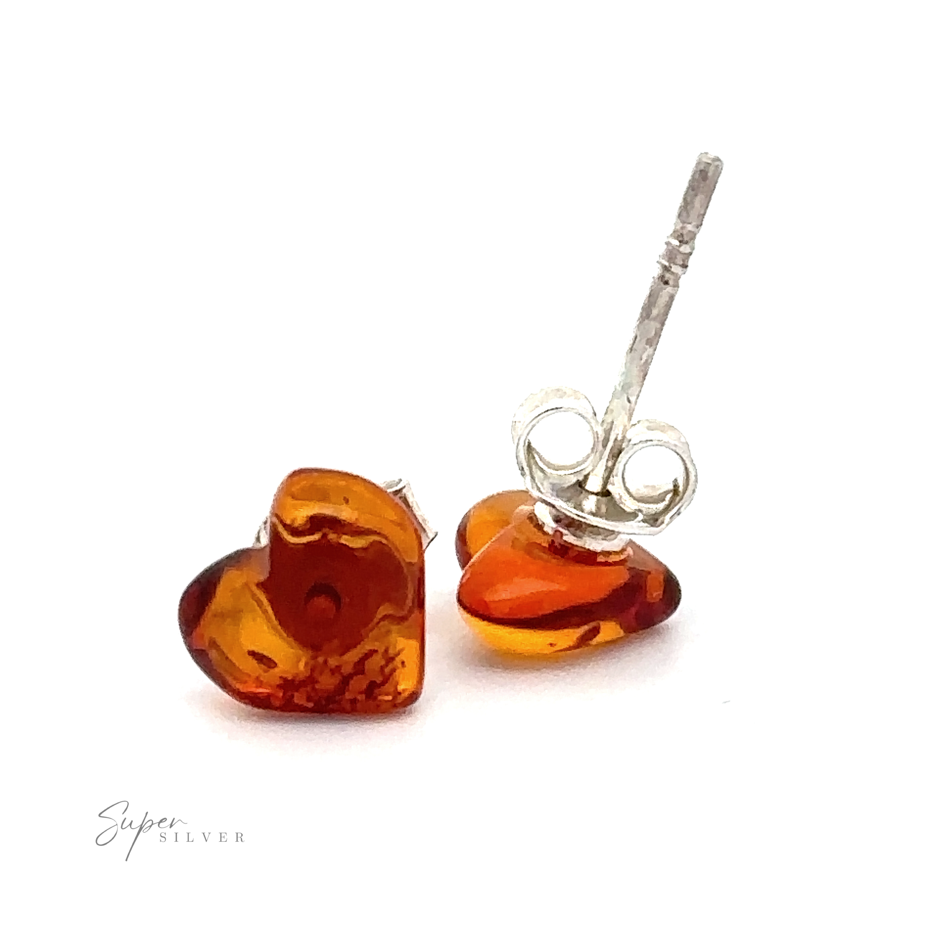 A pair of Amber Heart Studs made of amber and sterling silver. One earring stands upright while the other lies flat, showcasing their intricate design against a plain white background.