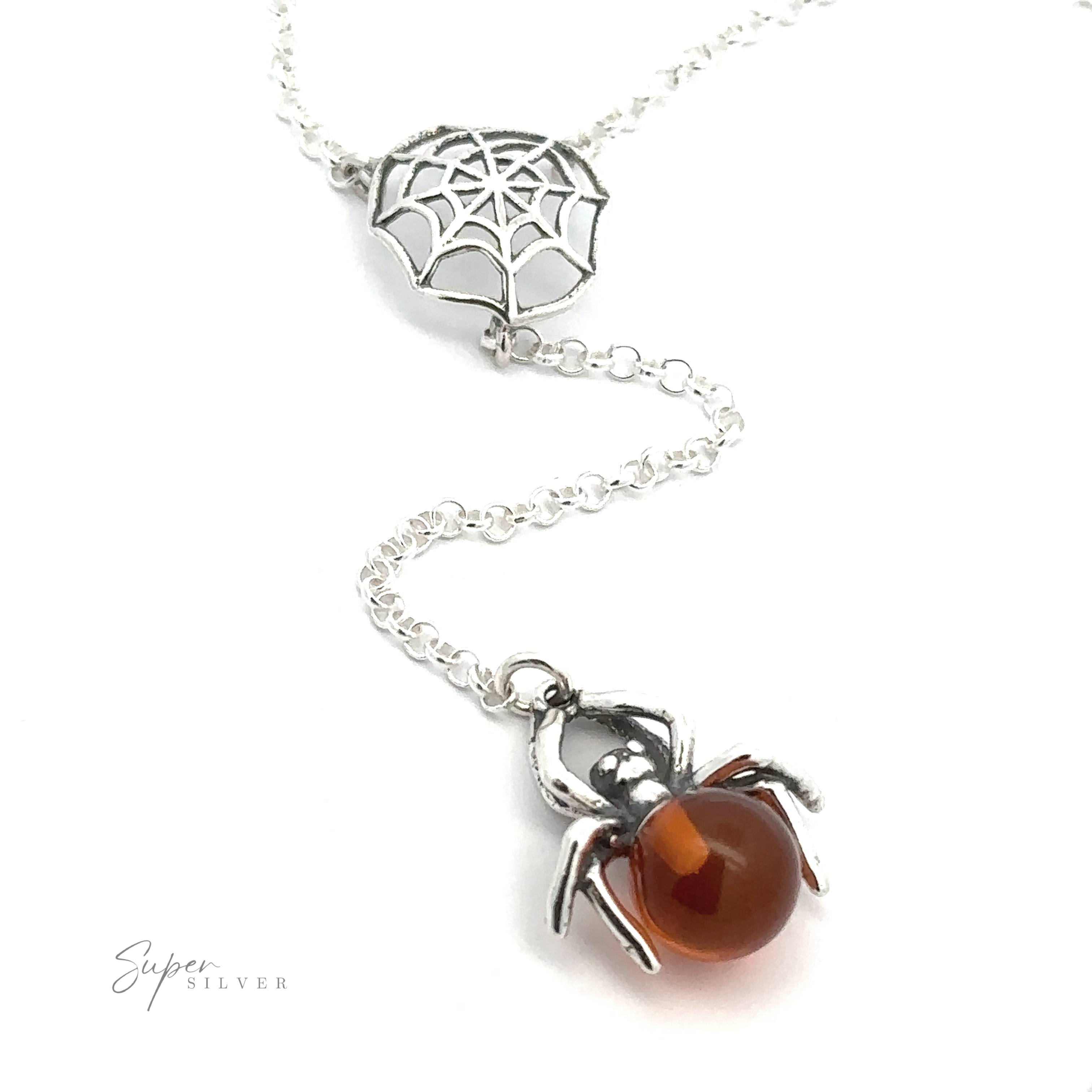 Baltic Amber Spider Necklace with a spider and spider web charm. The spider holds a round Baltic amber-like bead, adding a witchy vibe. The chain is thin and interlinked. The brand "Super Silver" is visible in the bottom left corner.