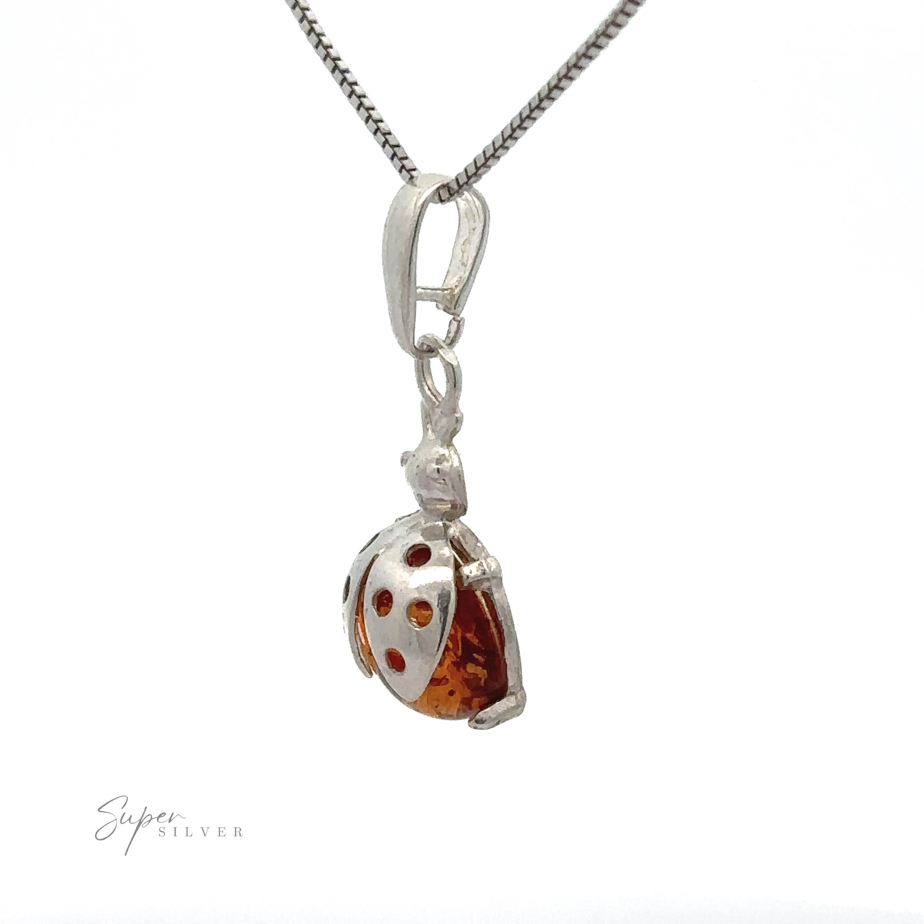A silver necklace featuring an Amber Ladybug Pendant adorned with Cognac Baltic Amber and red details, symbolizing good fortune jewelry.