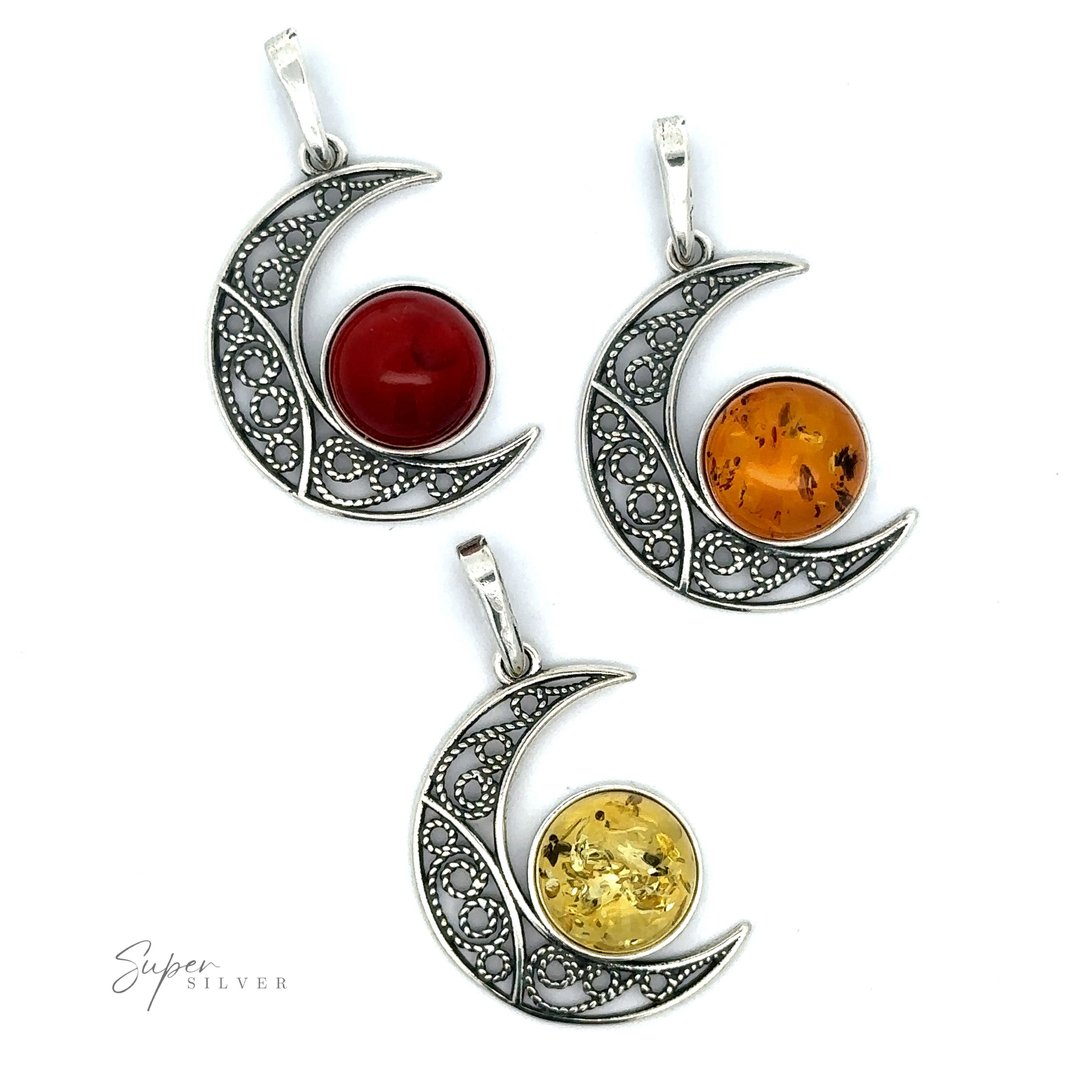 Three sterling silver crescent moon pendants with intricate designs, each featuring a central colored gemstone: red, orange, and yellow. One of them highlights a stunning Baltic Amber Moon Pendant.