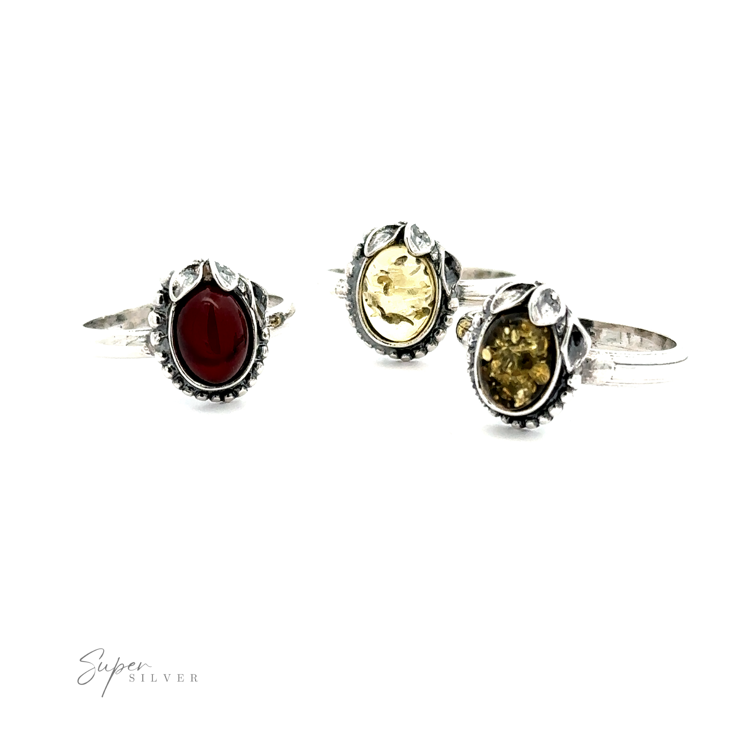Three Amber Rings with Beaded Border and Peace Lily Details, each exuding vintage elegance with oval gemstones: one red and two shades of yellow, set against a white background. The brand name "Super Silver" is visible in the bottom left corner, highlighting their nature-inspired jewelry collection.
