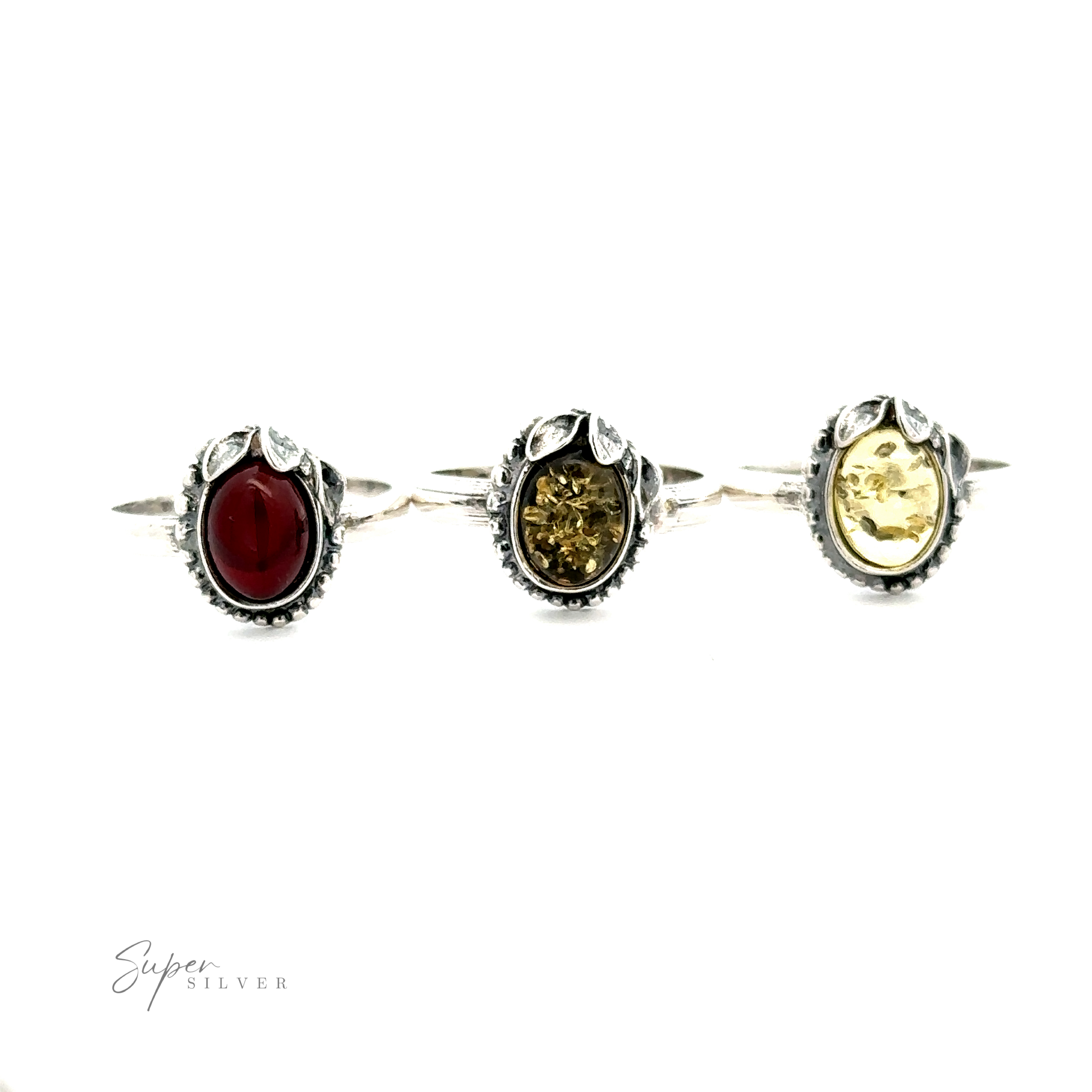 Three silver rings with ornate designs, each featuring an oval gemstone, exude vintage elegance. The gemstones are red, amber, and yellow in color. The Amber Ring with Beaded Border and Peace Lily Details stands out as a true piece of nature-inspired jewelry.