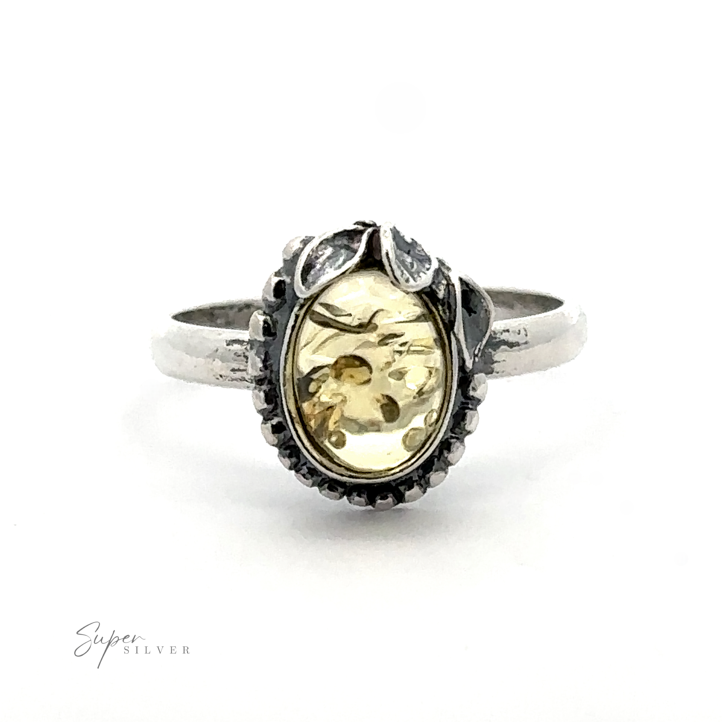 A silver ring featuring an oval-shaped yellow gemstone and a floral design on the band, exuding vintage elegance. This nature-inspired piece truly stands out as an Amber Ring with Beaded Border and Peace Lily Details.