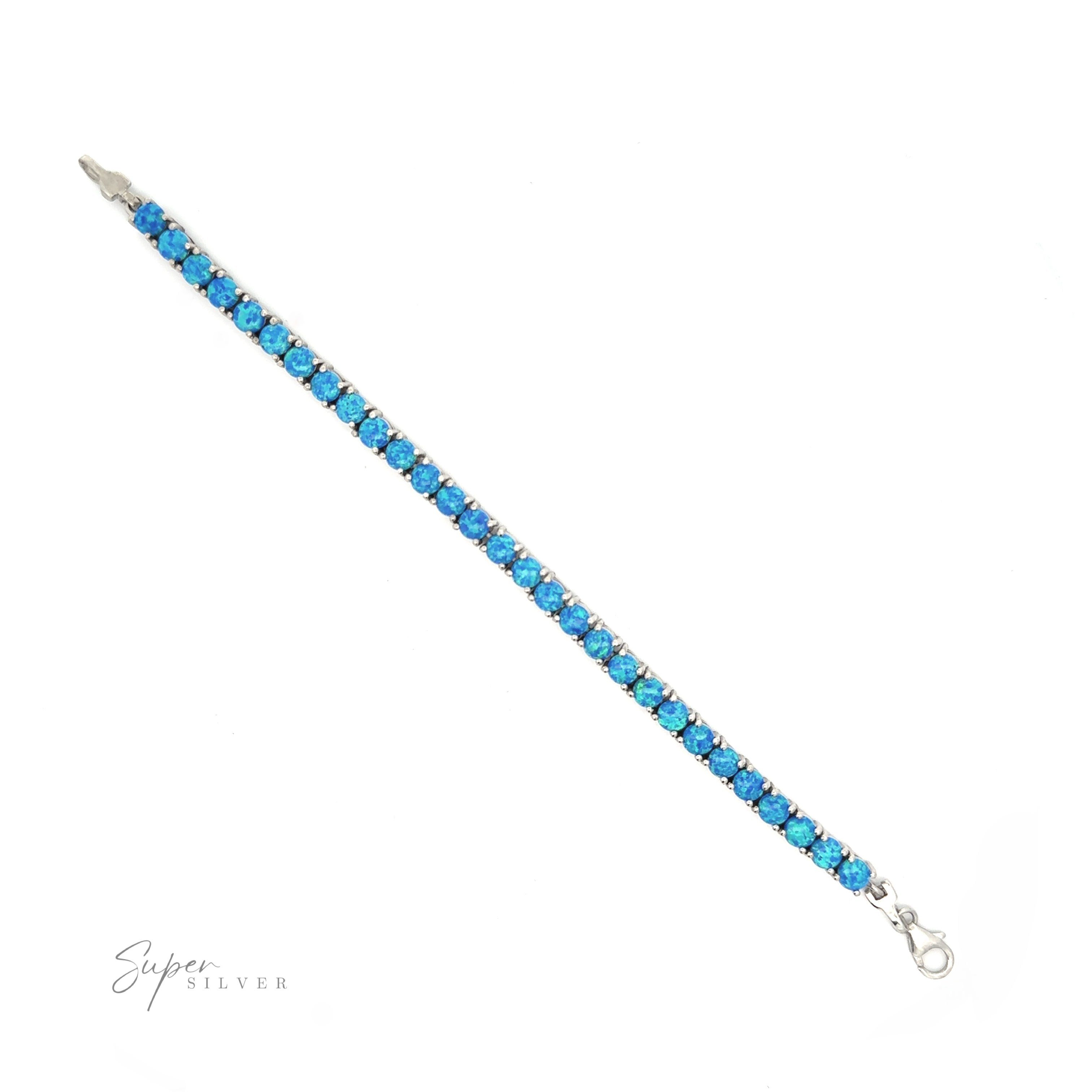 Brilliant Blue Opal Bracelet with blue gemstones arranged in a single line, secured with a lobster clasp, featuring a rhodium finish, on a white background. Signature at bottom right.