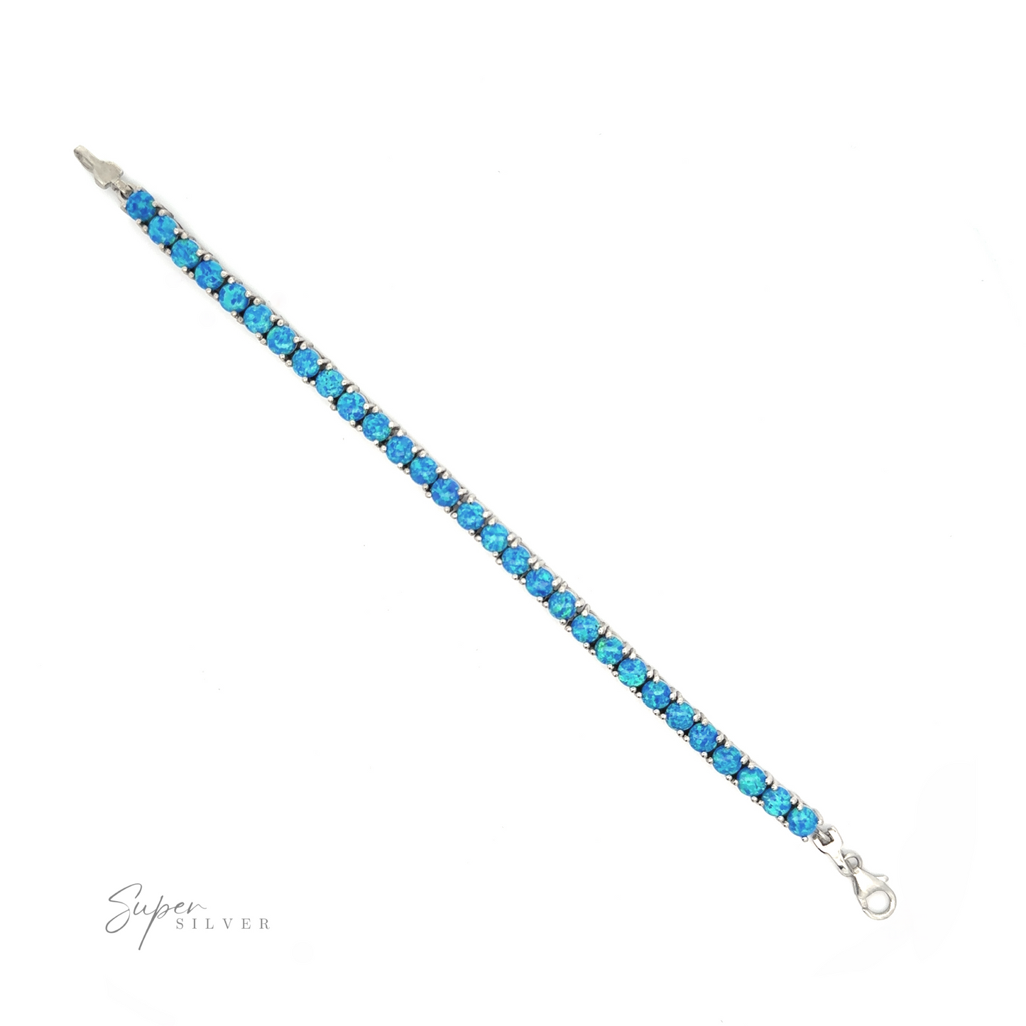 
                  
                    Brilliant Blue Opal Bracelet with blue gemstones arranged in a single line, secured with a lobster clasp, featuring a rhodium finish, on a white background. Signature at bottom right.
                  
                