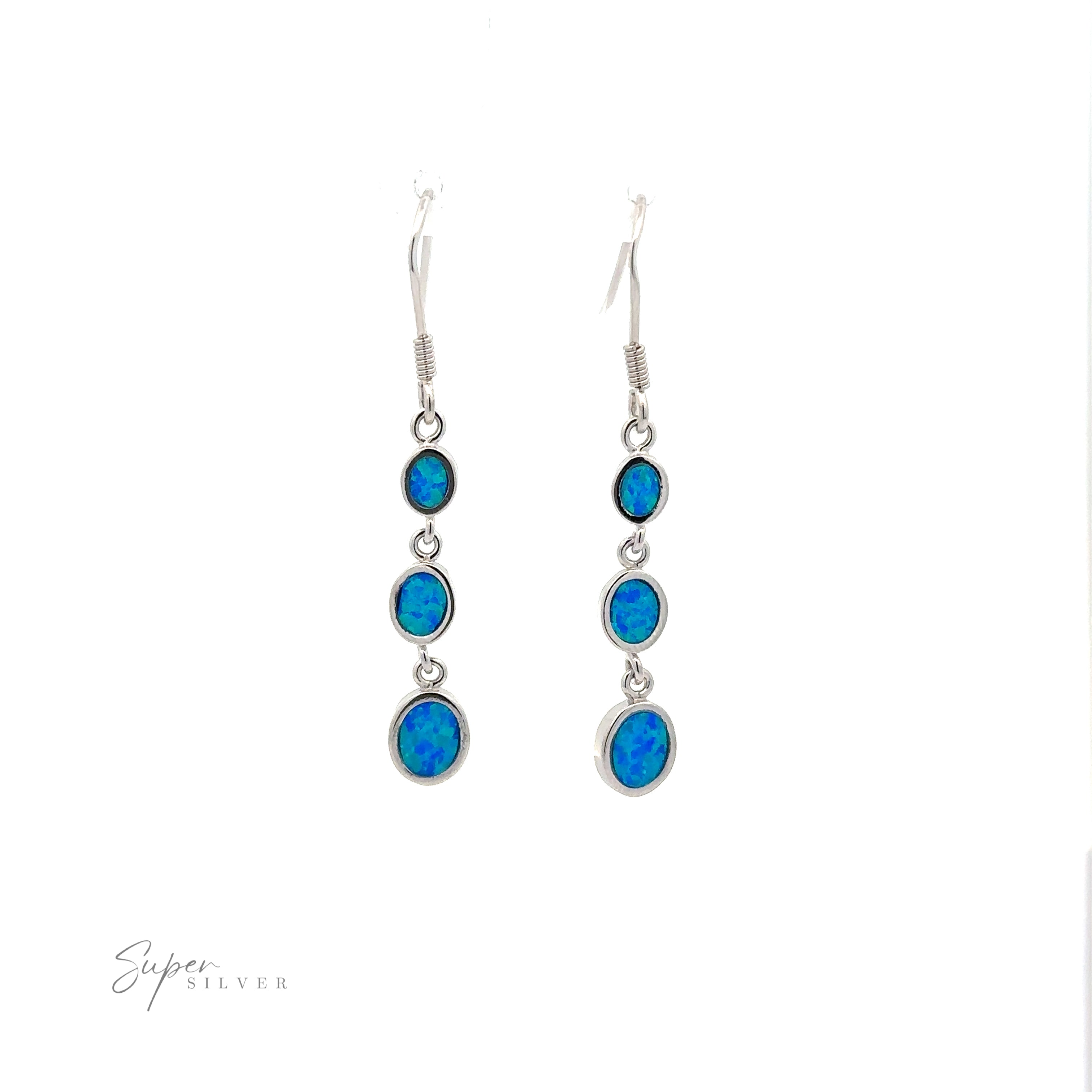 A pair of Long Oval Blue Lab-Created Opal Earrings featuring three round blue lab-created opal gemstones arranged in a vertical geometric design, with the largest gemstone at the bottom and the smallest at the top. "Super Silver" is inscribed at the bottom left.
