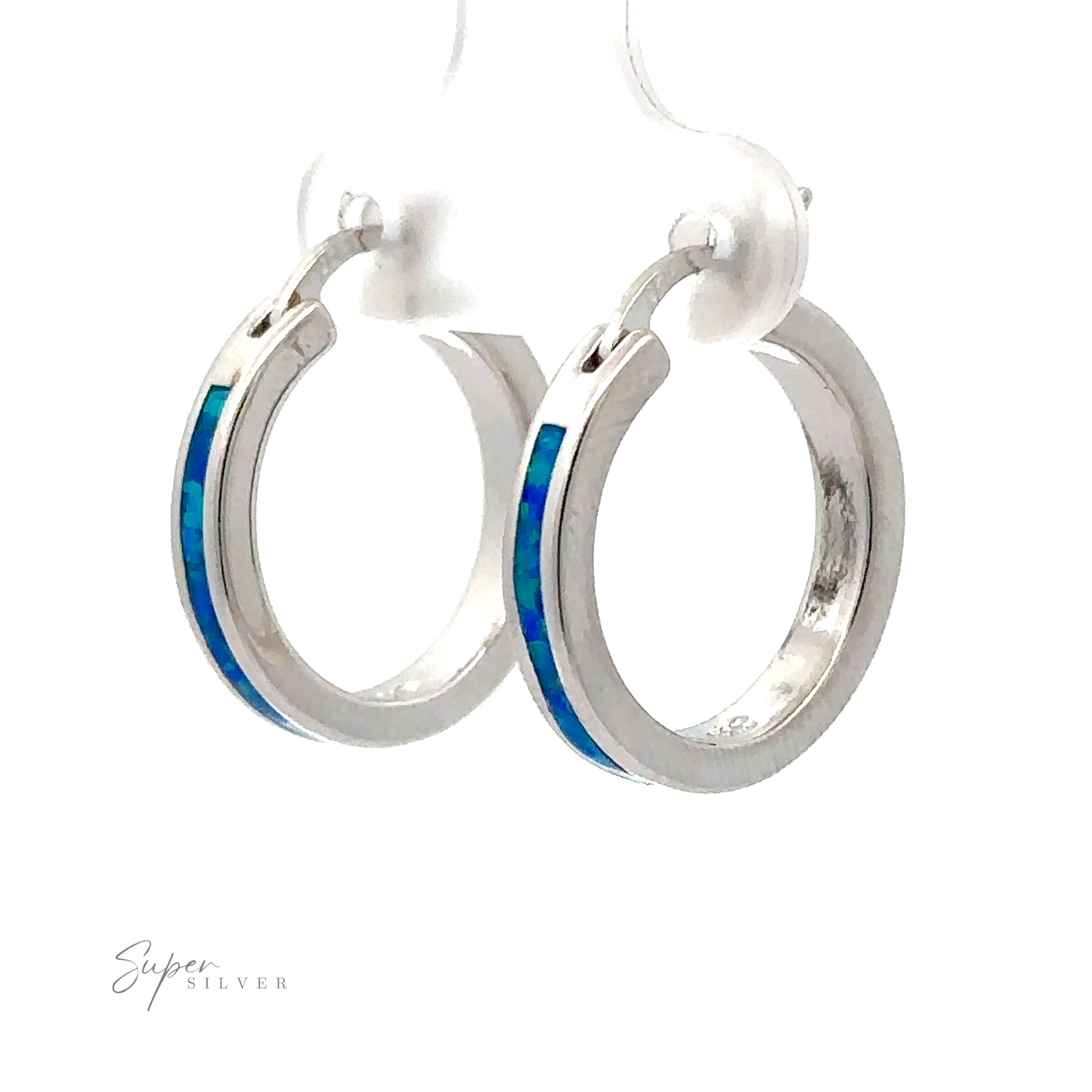 Close-up of the exquisite Blue Lab-Created Opal Hoop Earrings, featuring a shimmering blue lab opal inlay and a radiant rhodium finish, elegantly displayed on a transparent stand.