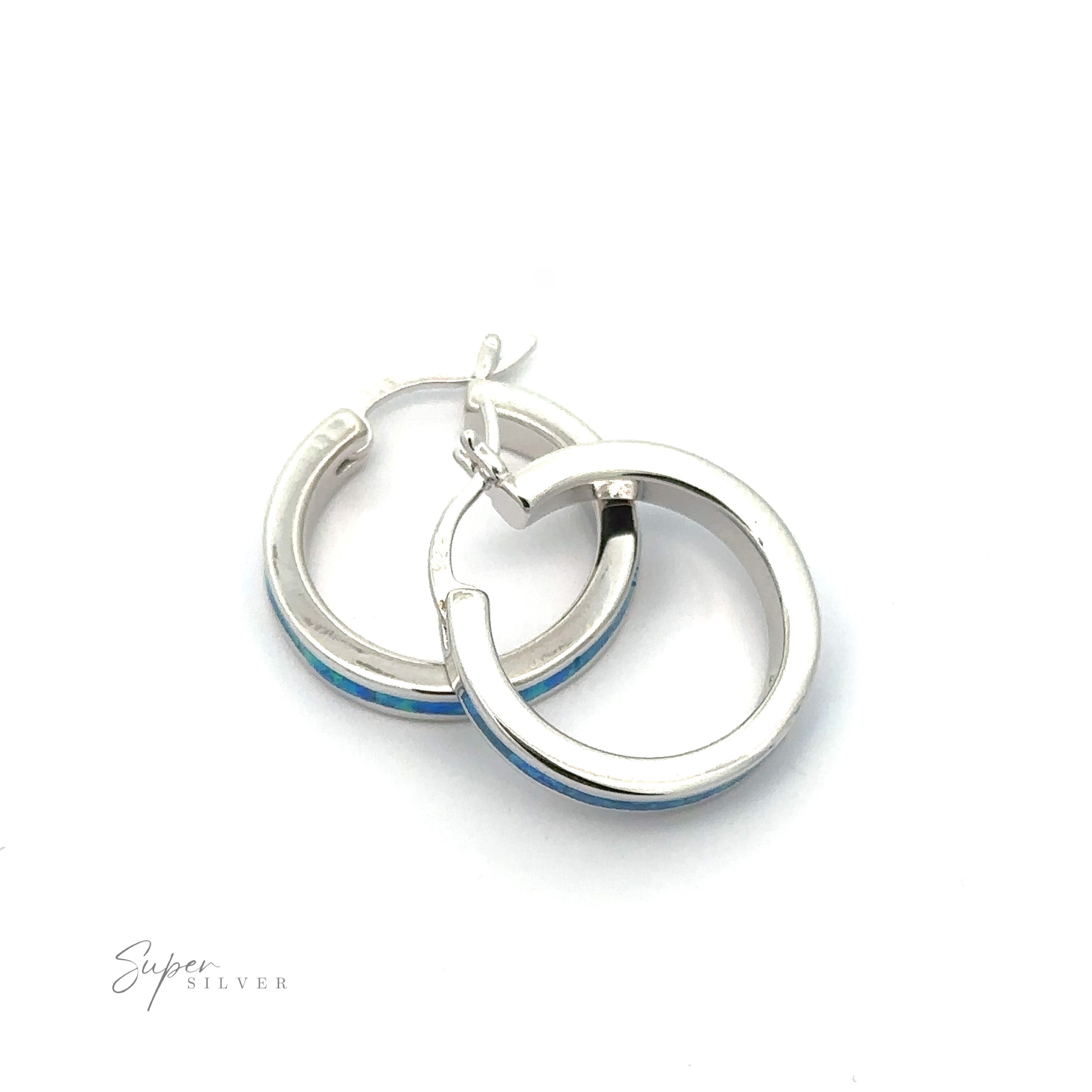 A pair of Blue Lab-Created Opal Hoop Earrings with a rhodium finish, showcasing a delicate blue lab-created opal accent along the outer edge, set against a white background.