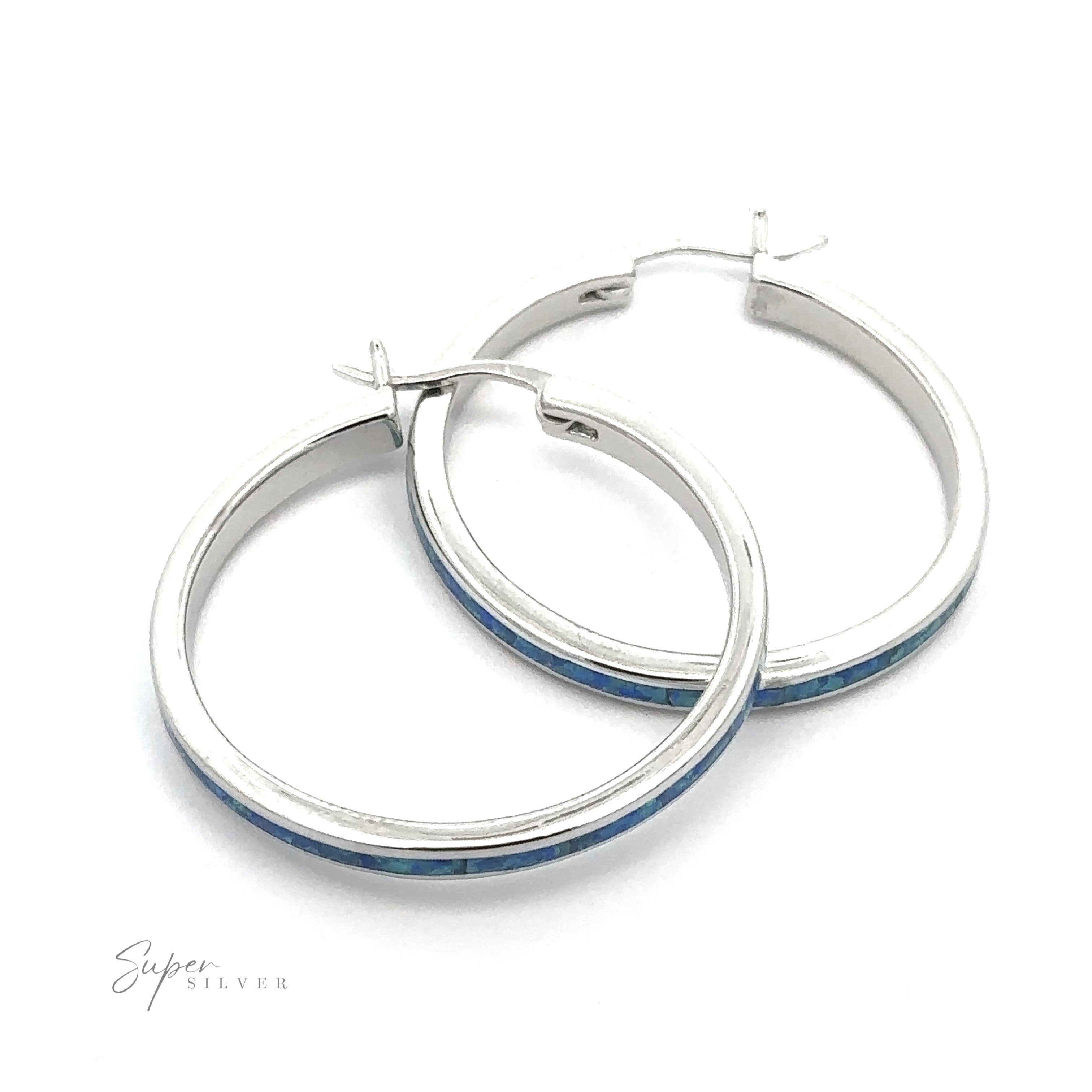 The Blue Lab-Created Opal Hoop Earrings showcase a striking blue opal inlay set against a pristine white background, all enhanced by a rhodium finish for added brilliance.
