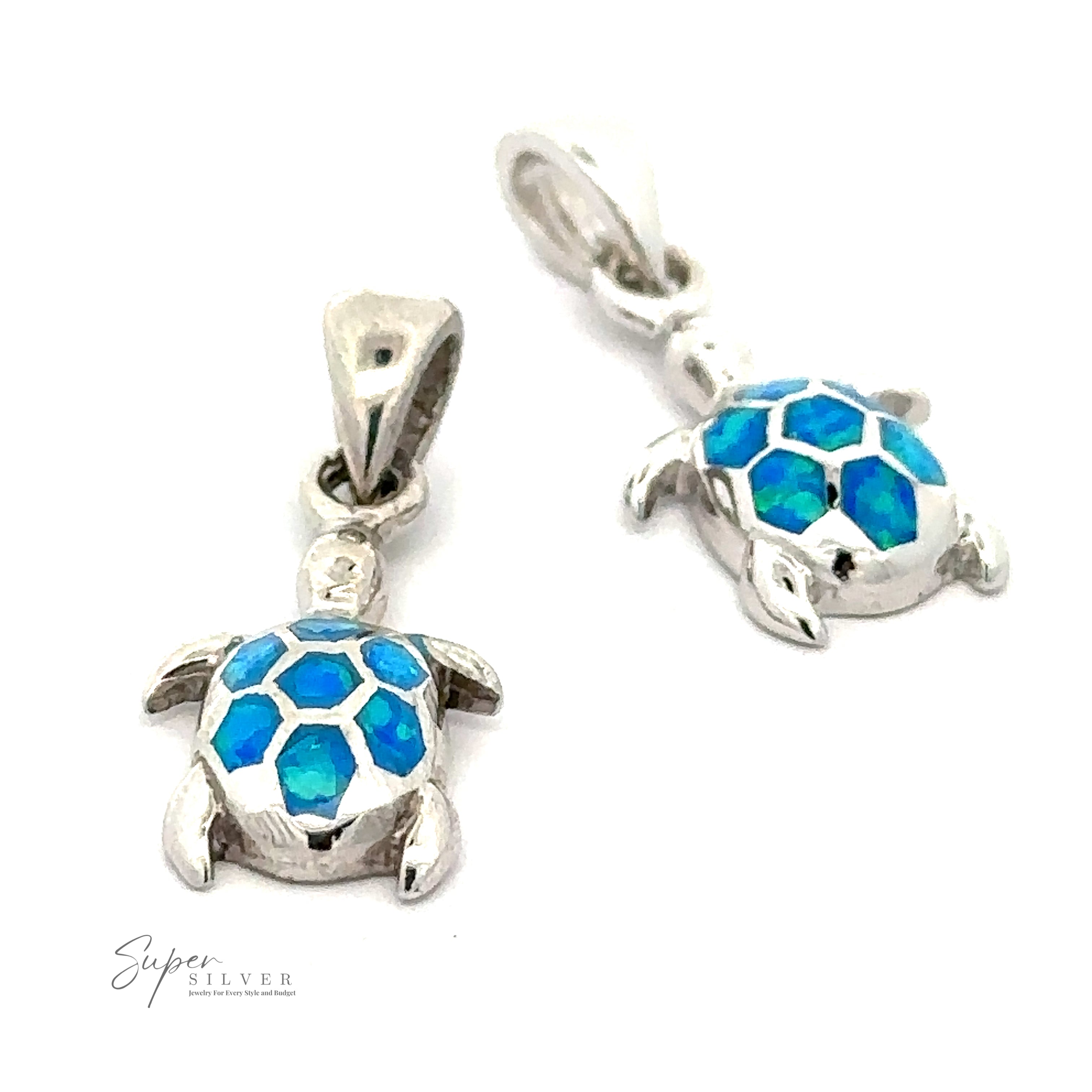 Two silver turtle pendants with blue opal stones creating a mosaic shell design. One pendant is lying flat, while the other stands upright, capturing the beauty of marine life. The Dainty Blue Opal Sea Turtle Pendant adds an elegant touch to any outfit.