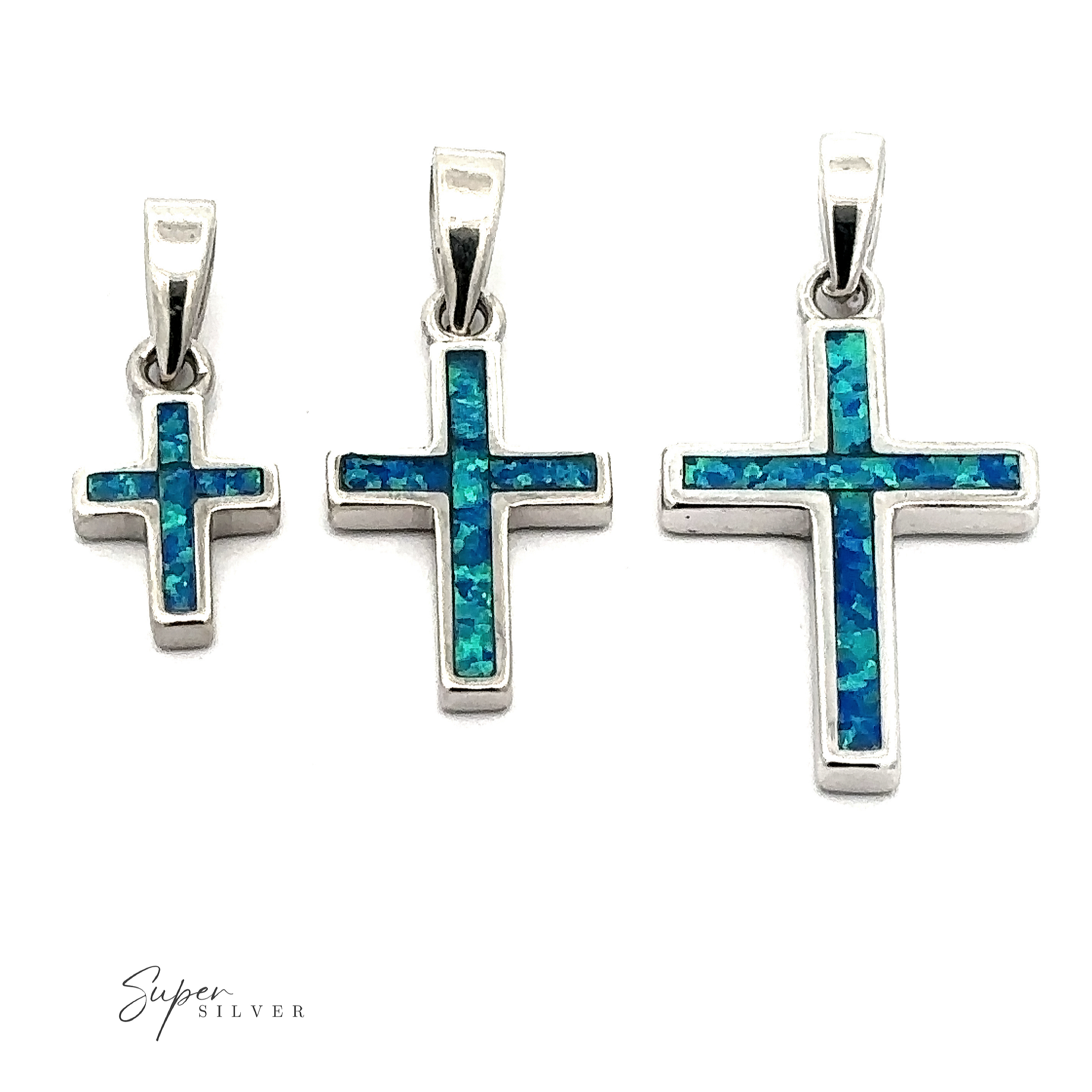 The Lab-Created Opal Cross Pendants in sterling silver beautifully showcase a captivating blue-green opal inlay, artistically set against a white background.
