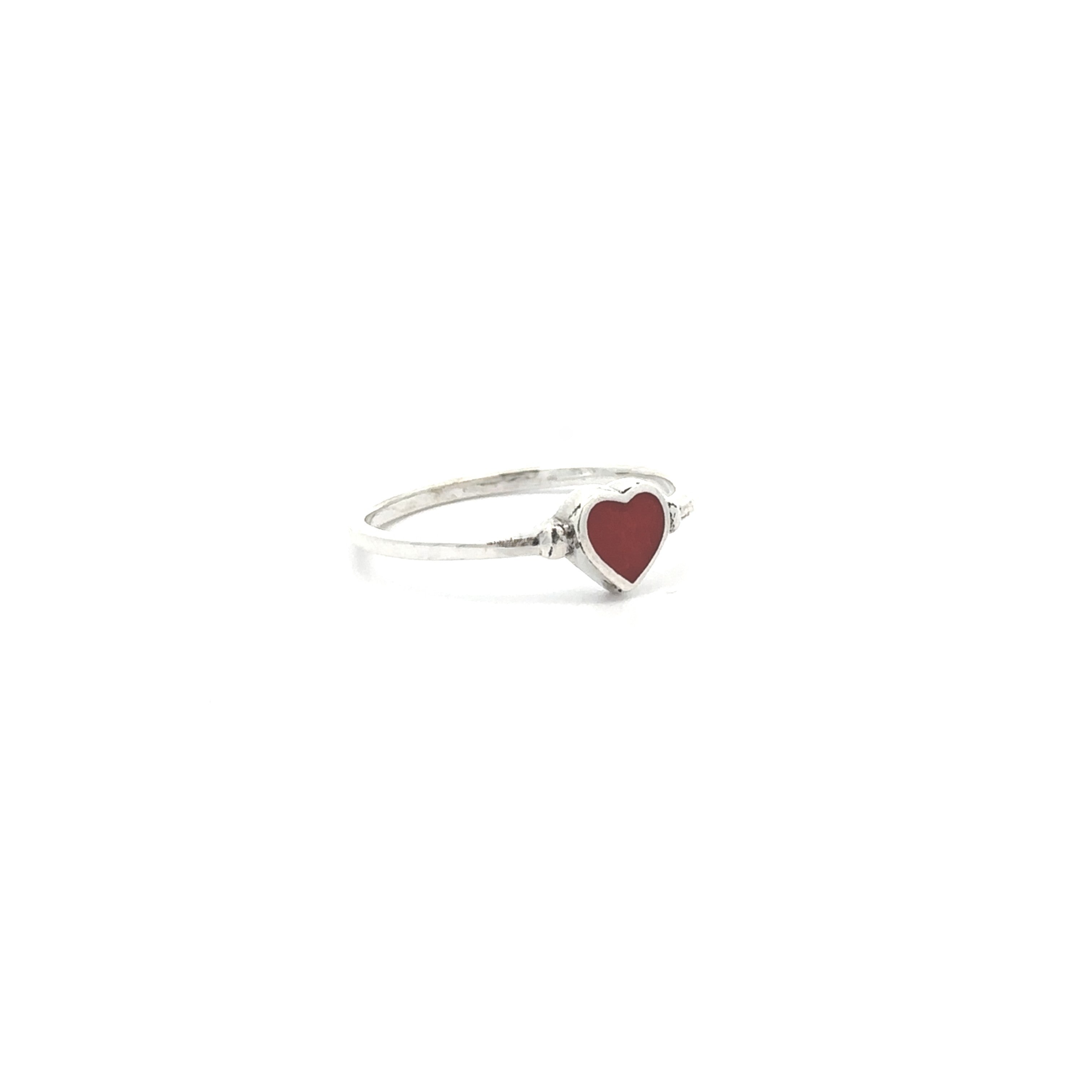 The Dainty Inlaid Heart Ring, featuring a sterling silver band and a red heart-shaped centerpiece, is displayed against a plain white background.