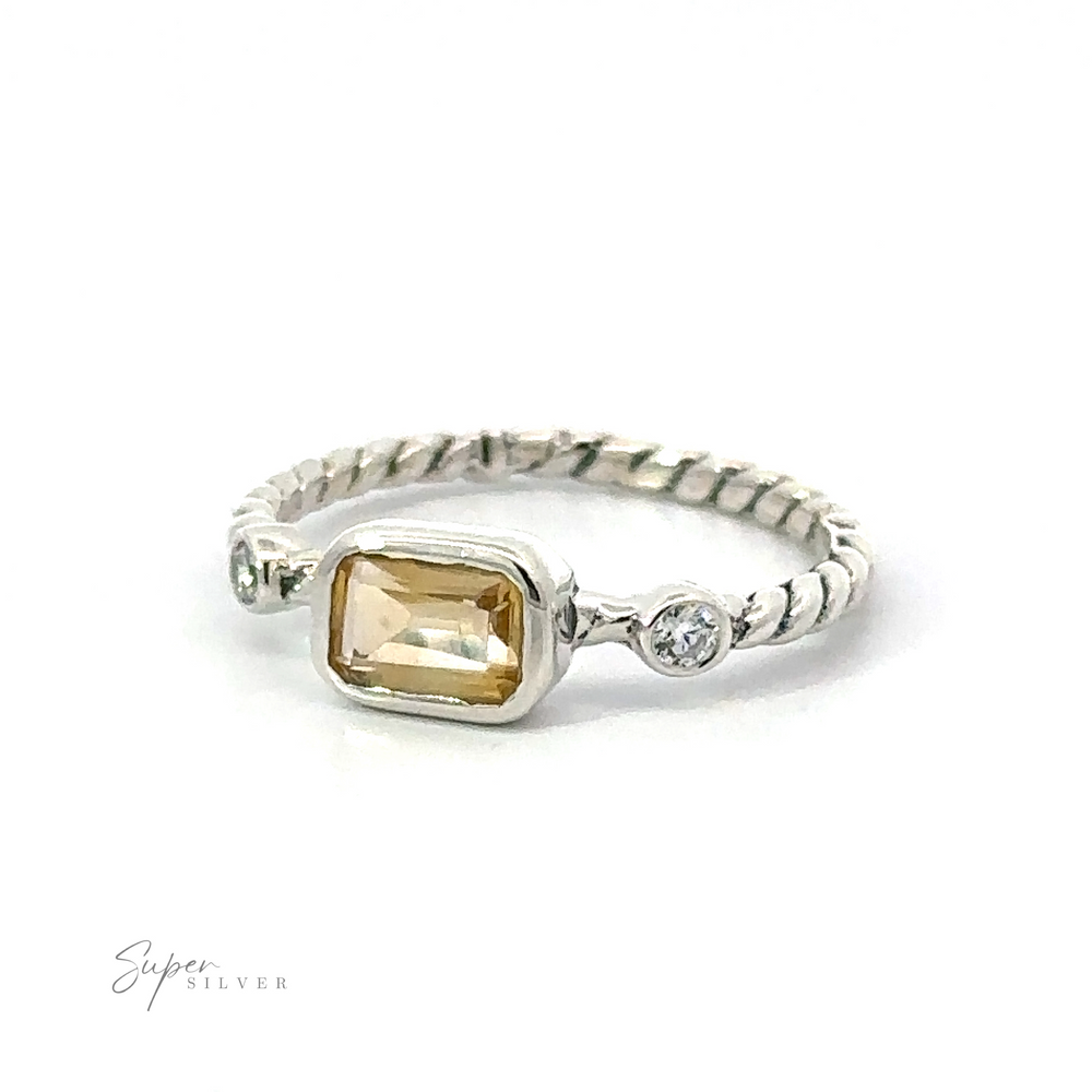 
                  
                    A vintage Rectangle Gemstone Ring with Twisted Band featuring a central rectangular yellow gemstone flanked by two small round diamonds, set on a plain white background.
                  
                
