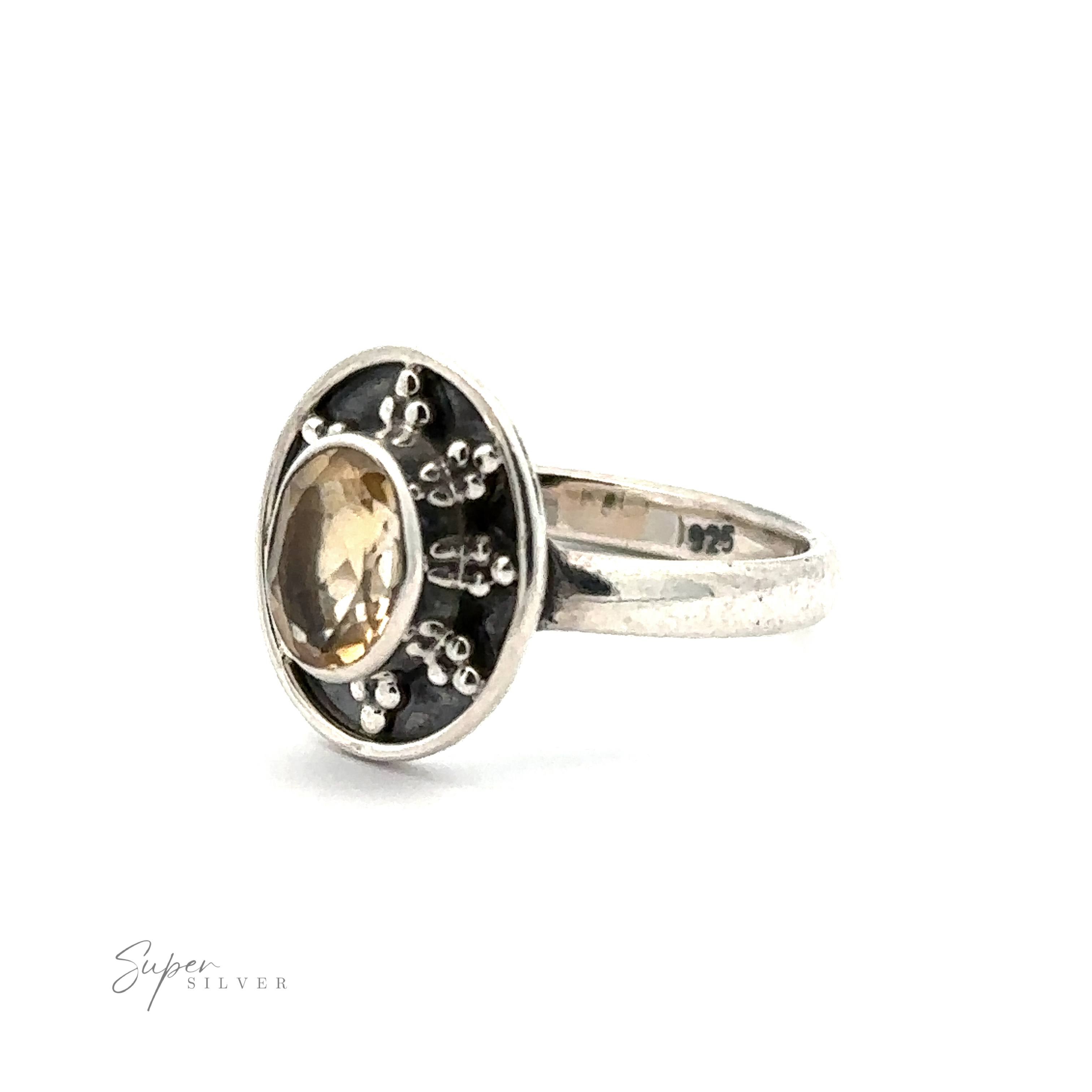 An Oval Gemstone Ring with Ball and Disk Border with an oval-shaped yellow stone set in a dark background, adorned with small silver embellishments. Imprinted with "925" indicating its classic gemstone ring composition, this piece exudes vintage-inspired jewelry charm.
