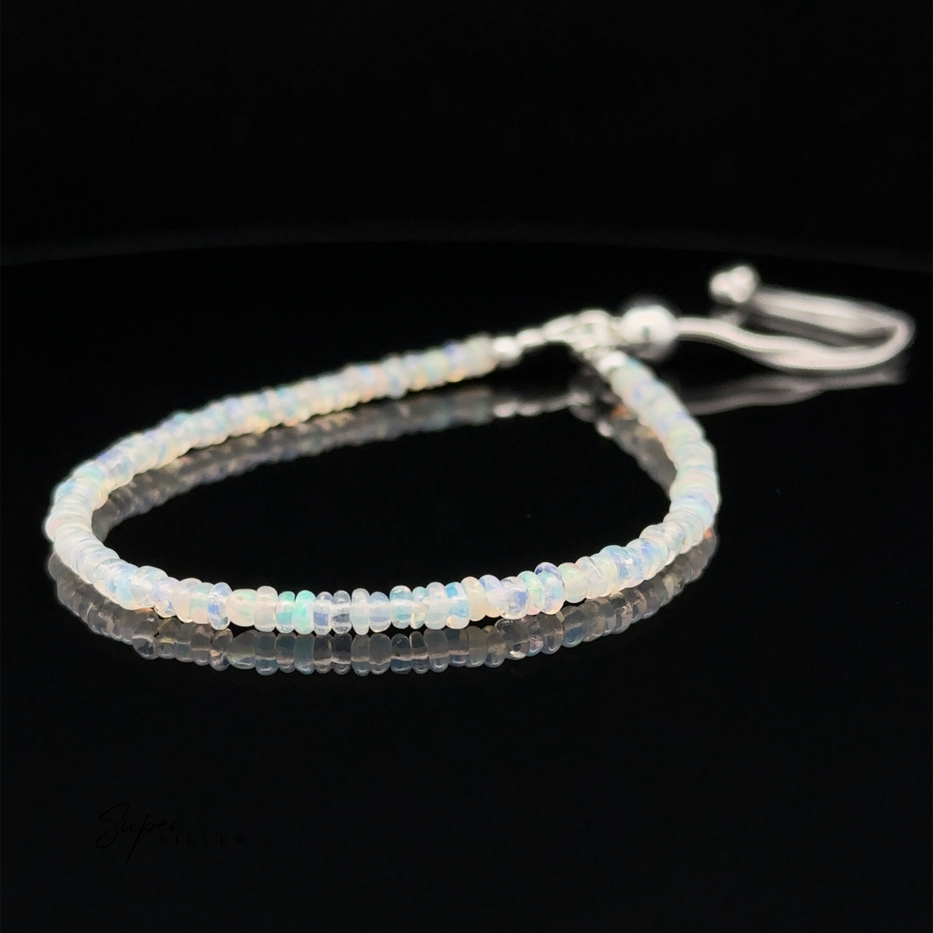 An Ethiopian Opal Beaded Bracelet with a sliding clasp, displayed on a black reflective surface. This beaded bracelet features an adjustable length closure for the perfect fit.