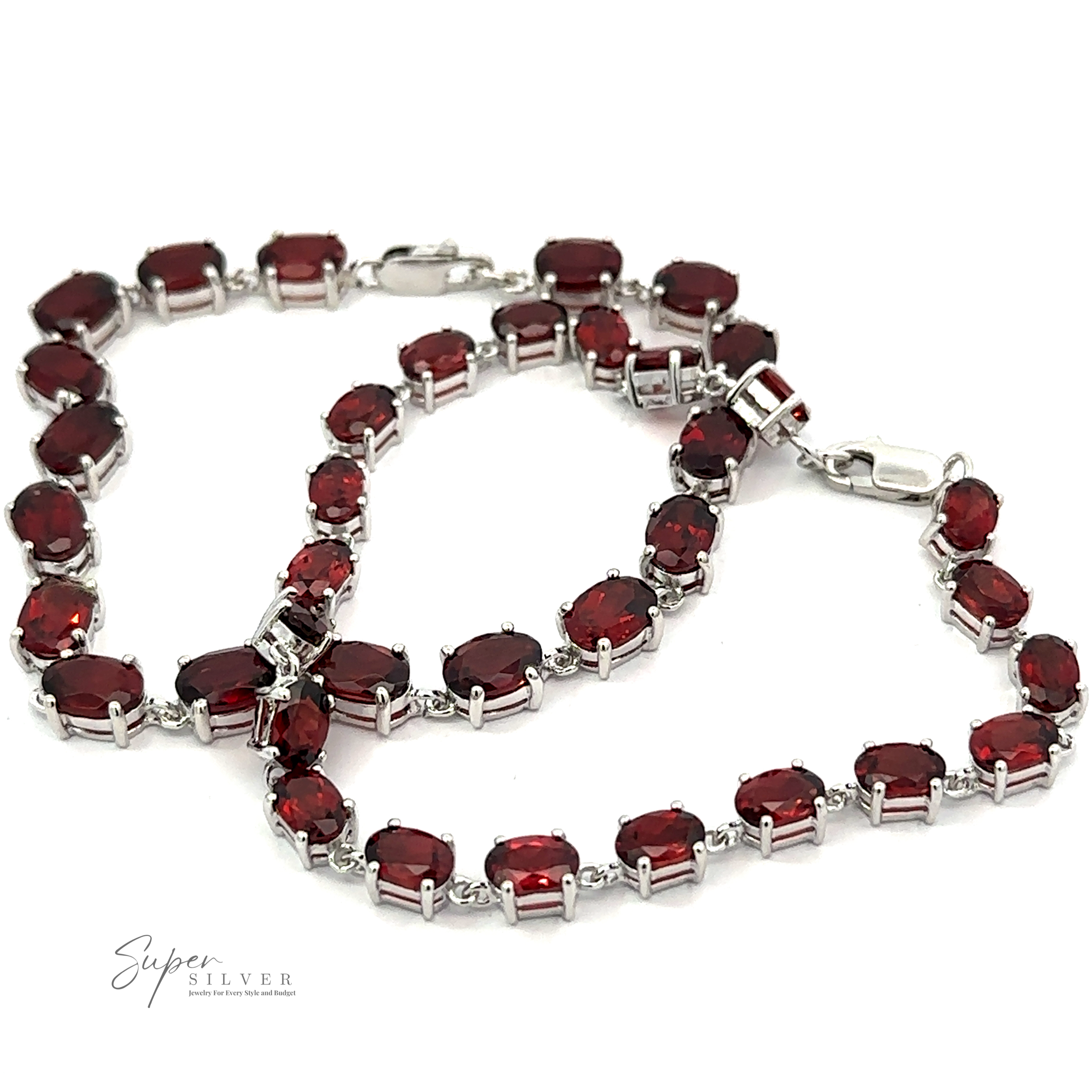 A Pronged Garnet Bracelet With Rhodium Finish adorned with a silver chain and multiple oval-shaped red garnet gemstones.