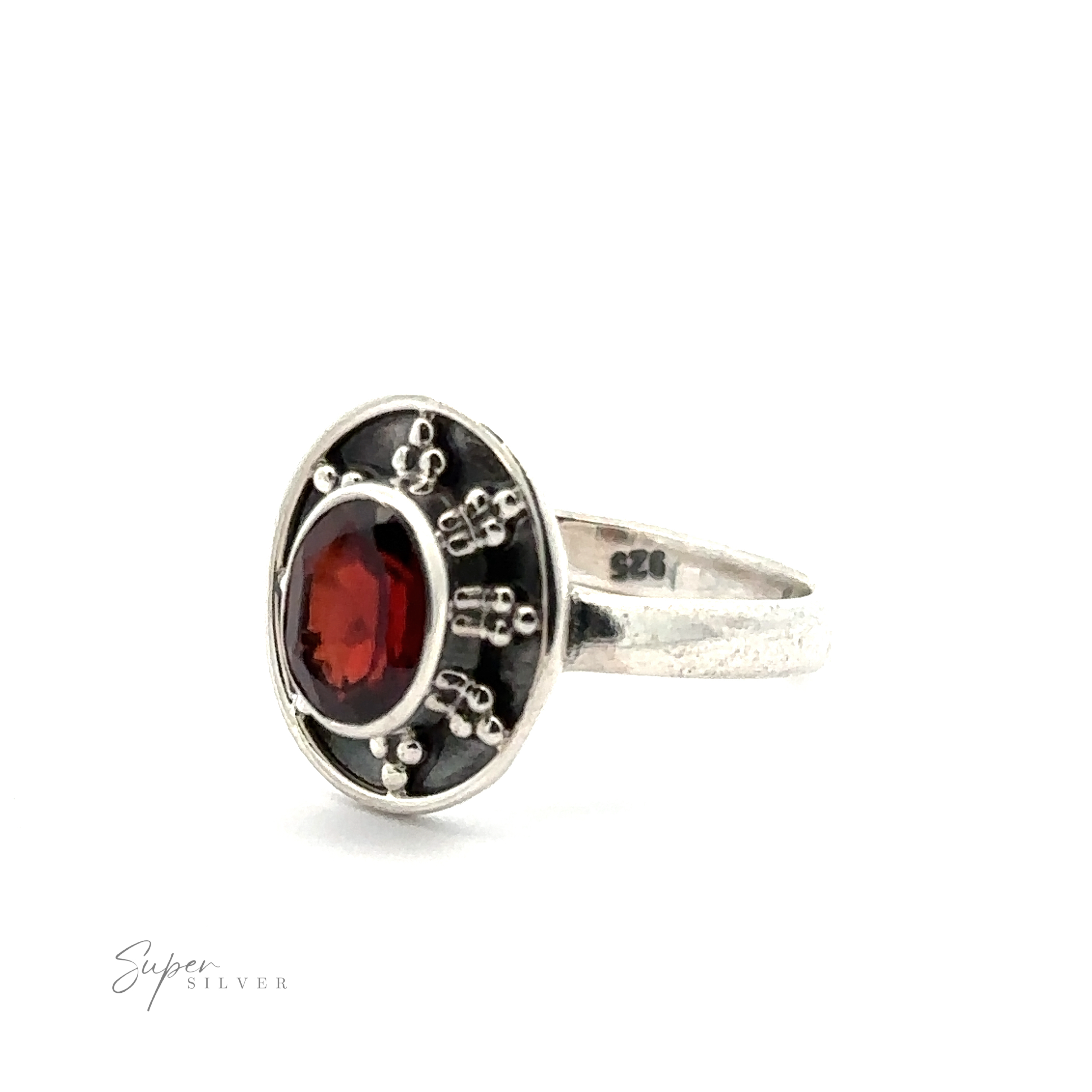 A Oval Gemstone Ring with Ball and Disk Border with a red gemstone set in an intricate, oval-shaped bezel. The band is stamped with "925," and the faint text "Super Silver" is visible in the bottom left corner, giving it a vintage-inspired jewelry appeal.