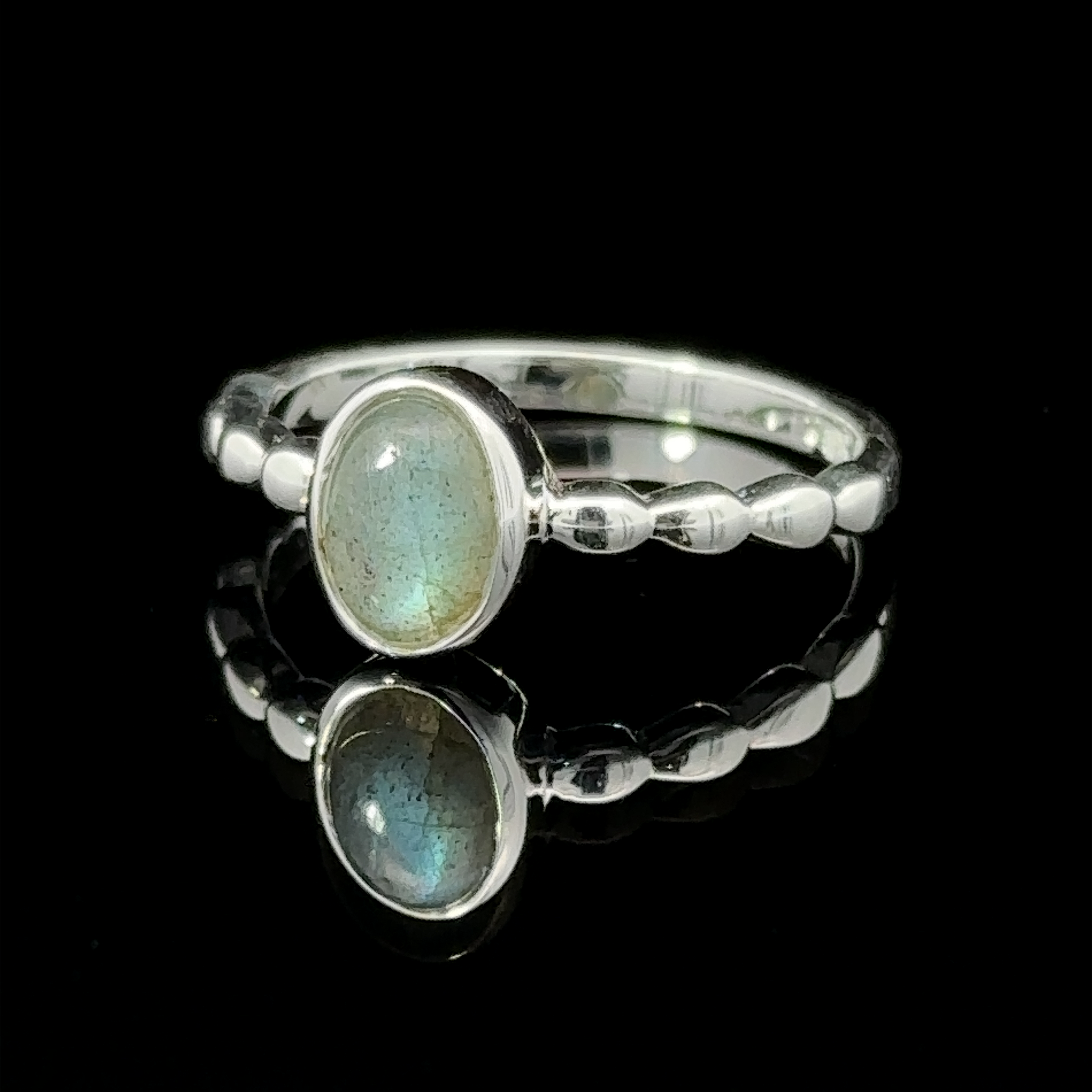 Oval Gemstone Ring with Beaded Band with a reflective opal stone set in the center, displayed against a black background.