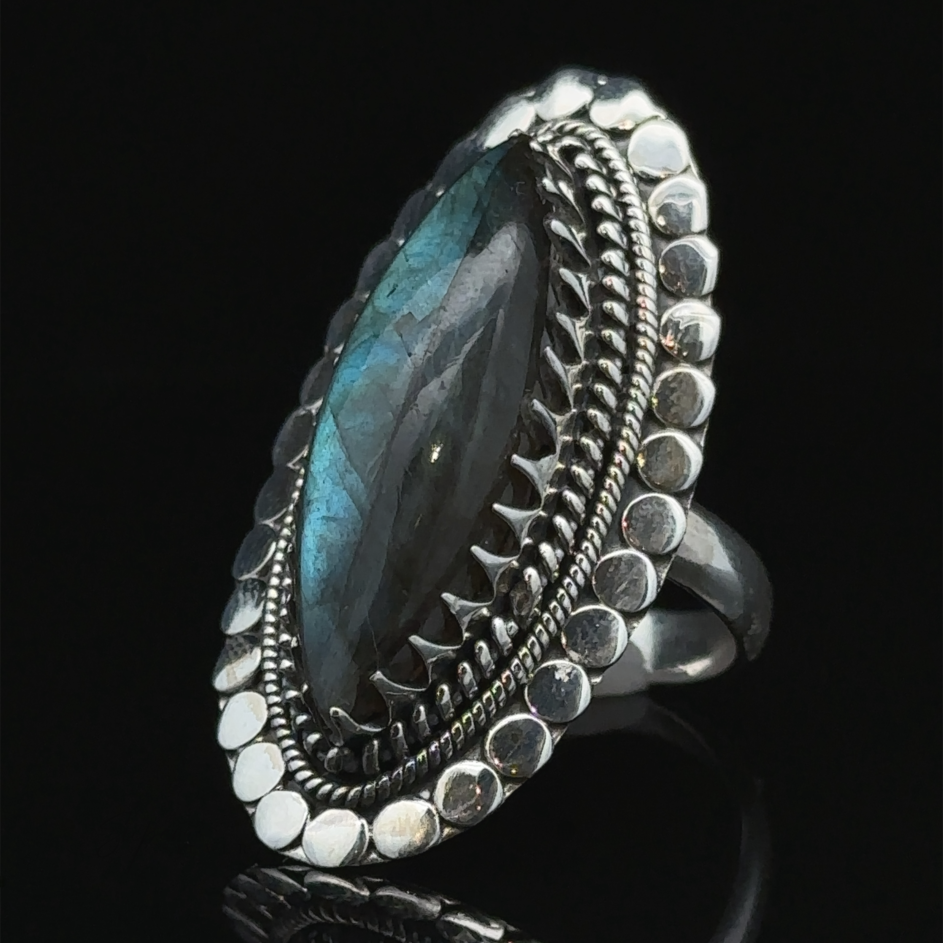 A Statement Marquise Shaped Gemstone Ring, featuring a beaded and ornate border, set against a black background.