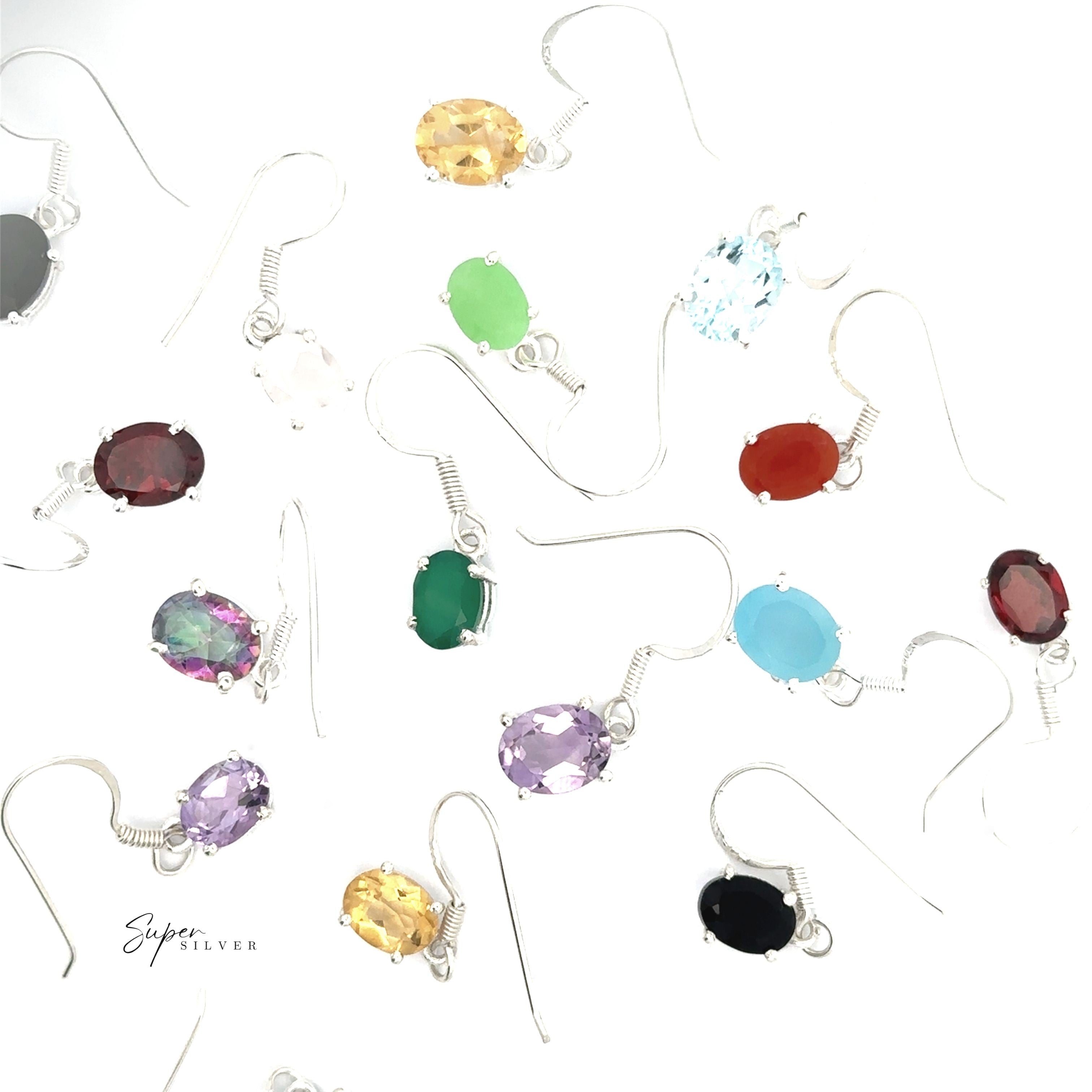 Brilliant Oval Gemstone Earrings in sterling silver feature oval settings with gemstones in black, green, red, purple, yellow, blue, and clear—beautifully arranged on a white background to add elegance to any look.