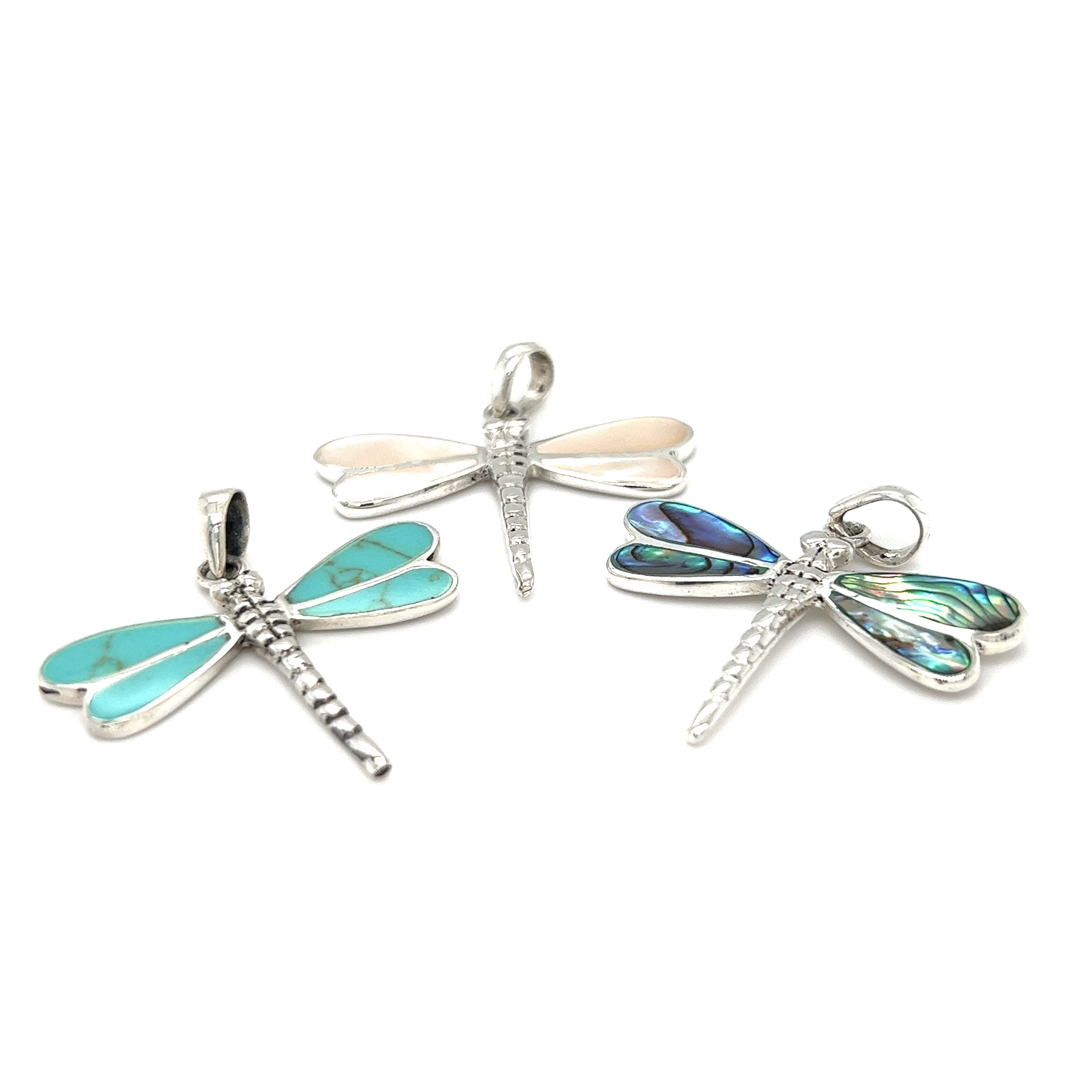 Three Dragonfly Inlay Stone Pendants with mother of pearl accents on a white background, produced by Super Silver.