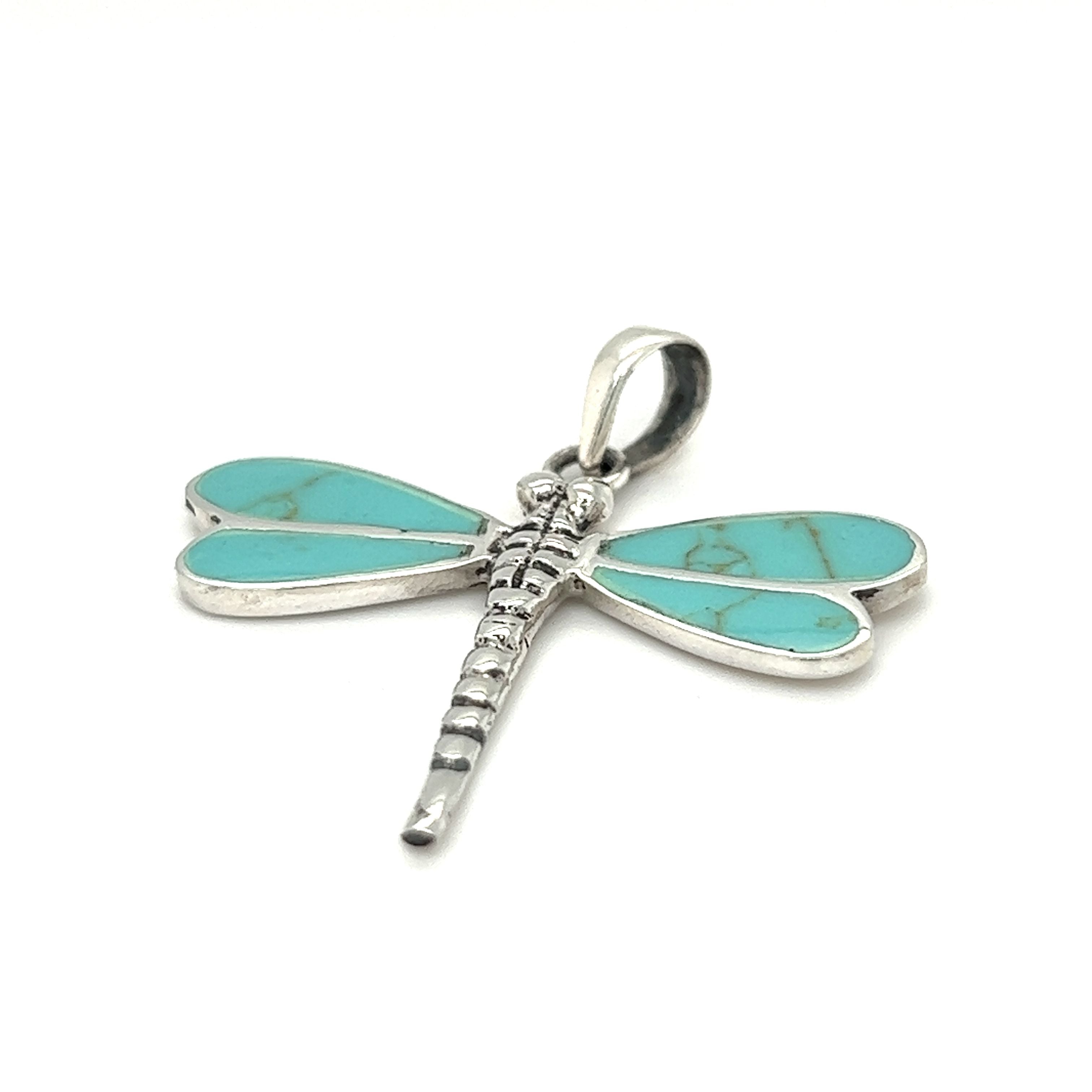 A Super Silver dragonfly pendant with turquoise stones and mother of pearl accents.