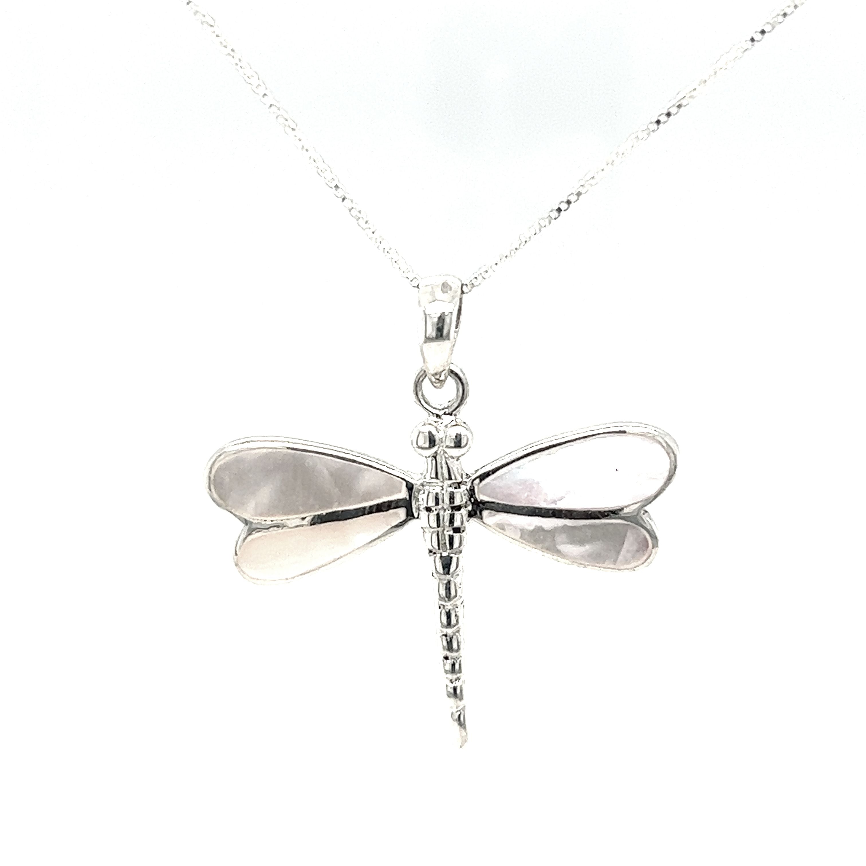 A stunning Super Silver Dragonfly Inlay Stone pendant adorned with intricate mother of pearl detailing, elegantly hanging from a delicate chain.