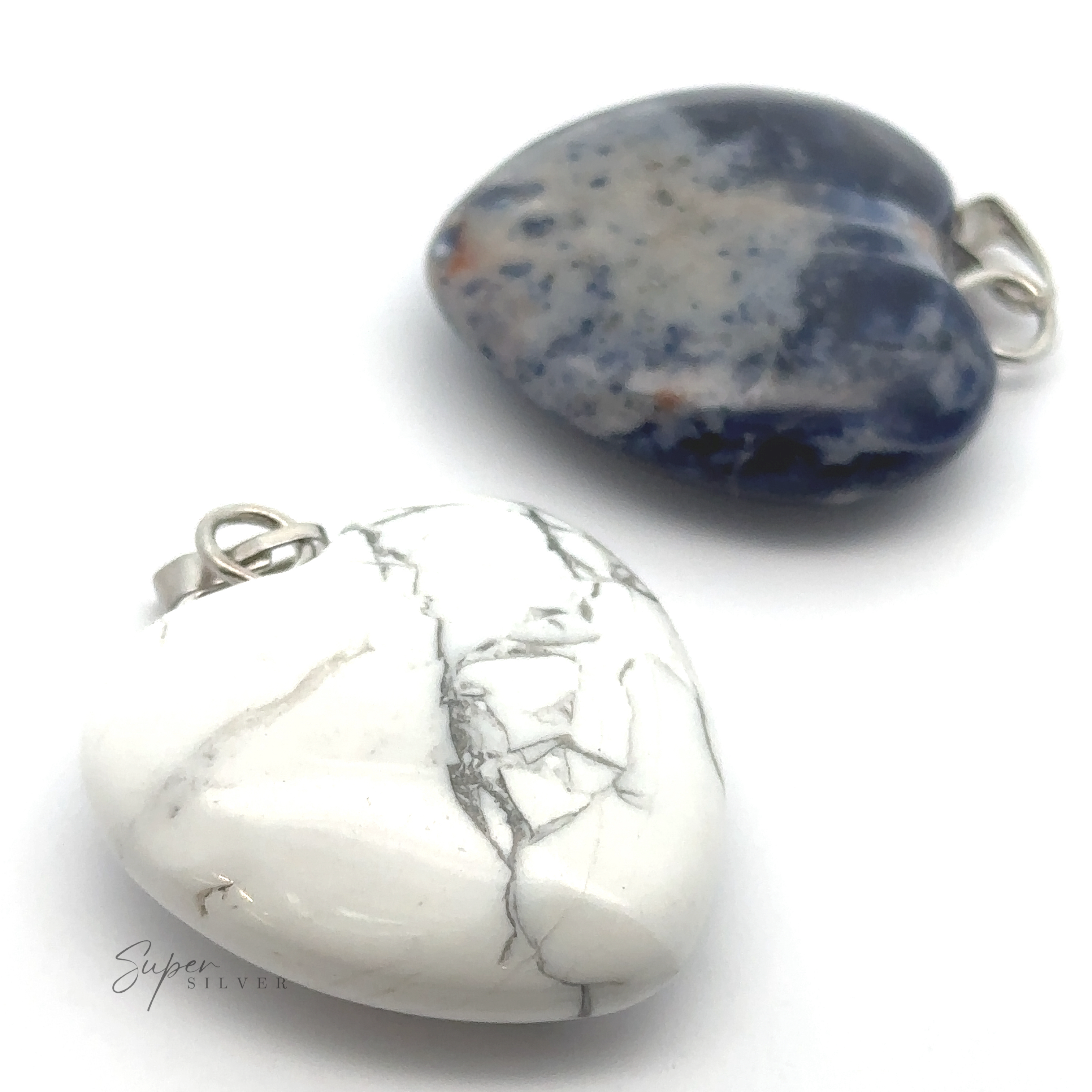 Two Heart Stone Pendant, perfect for everyday wear, one white with gray veins and the other mottled blue and gray, are elegantly displayed against a white background.