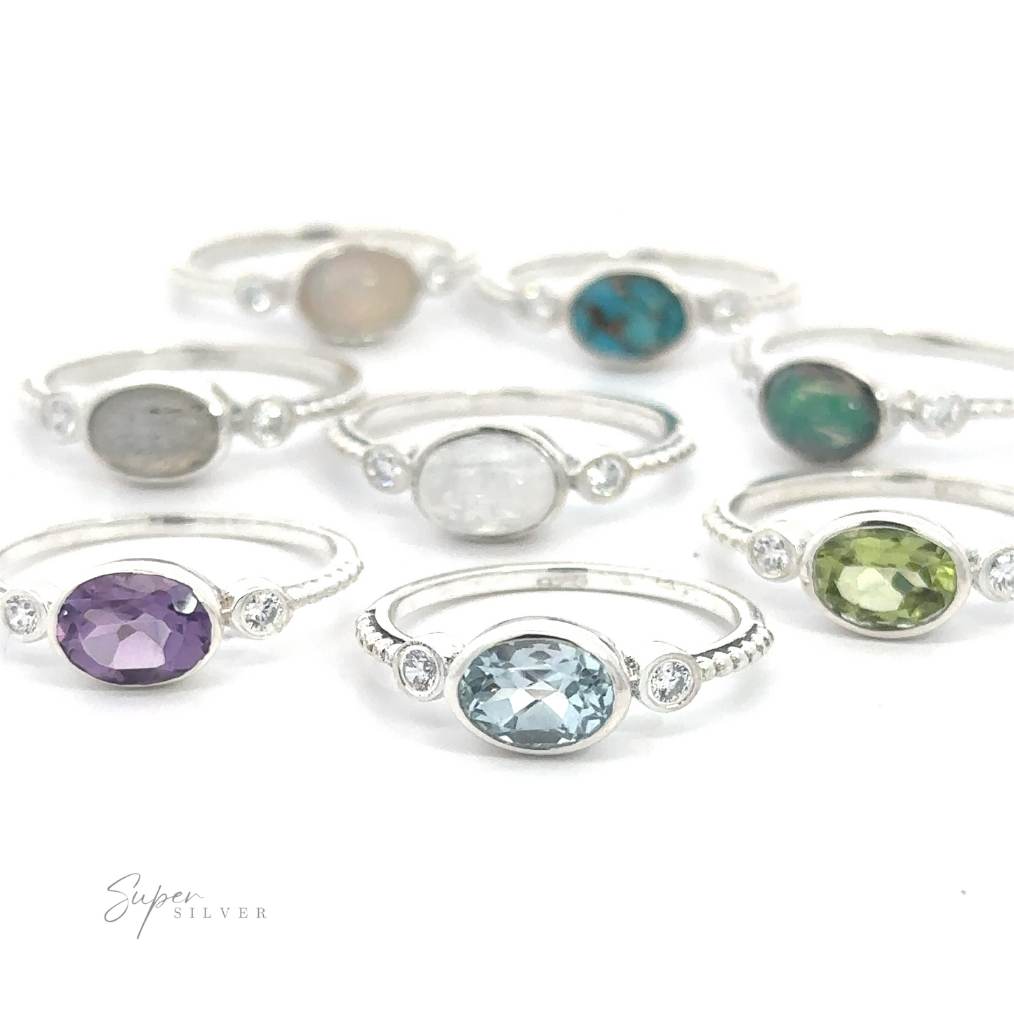 An assortment of handcrafted Horizontal Oval Gemstone Rings with Beaded Bands, displayed on a white surface.