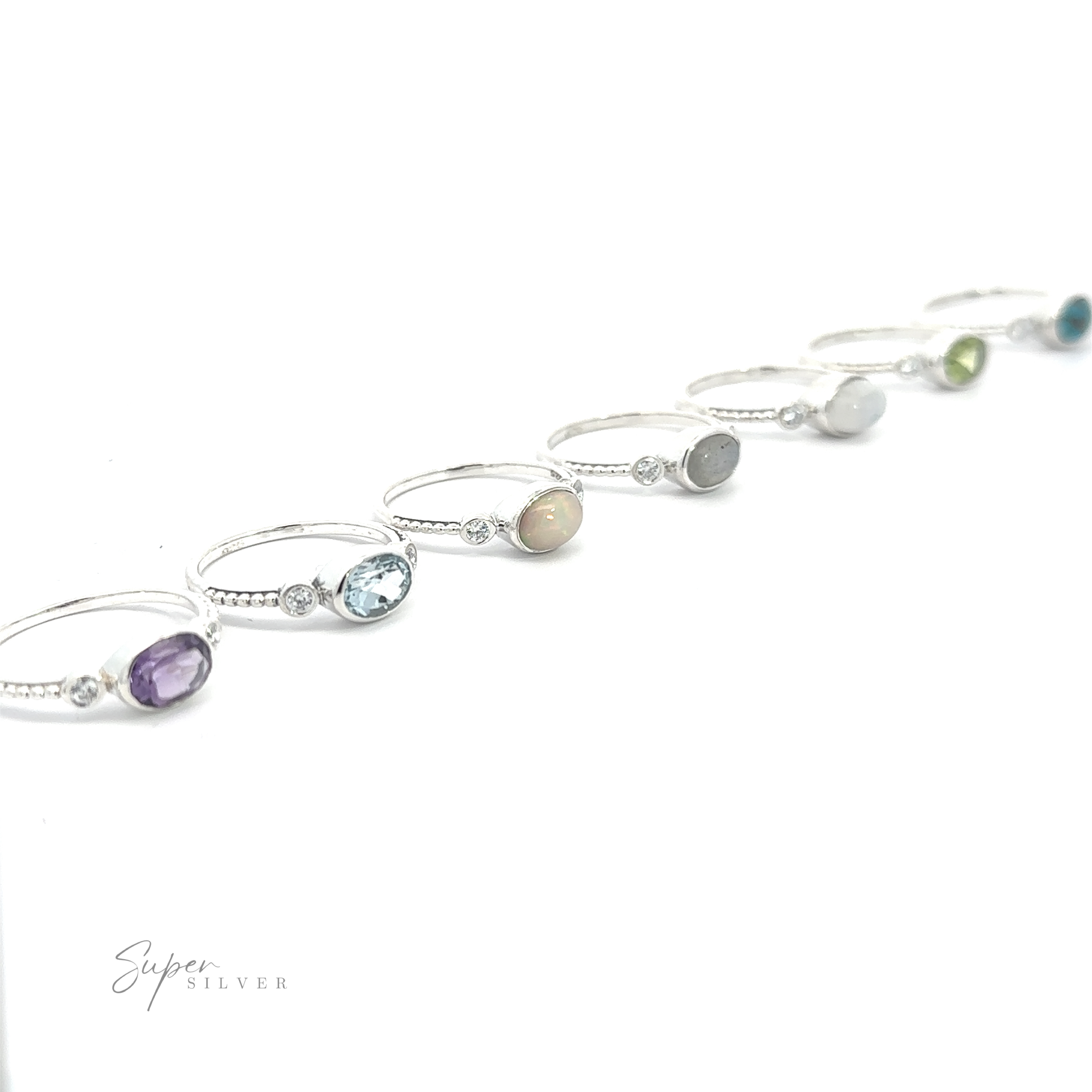 Several Horizontal Oval Gemstone Rings with Beaded Bands displayed in a row on a white background.