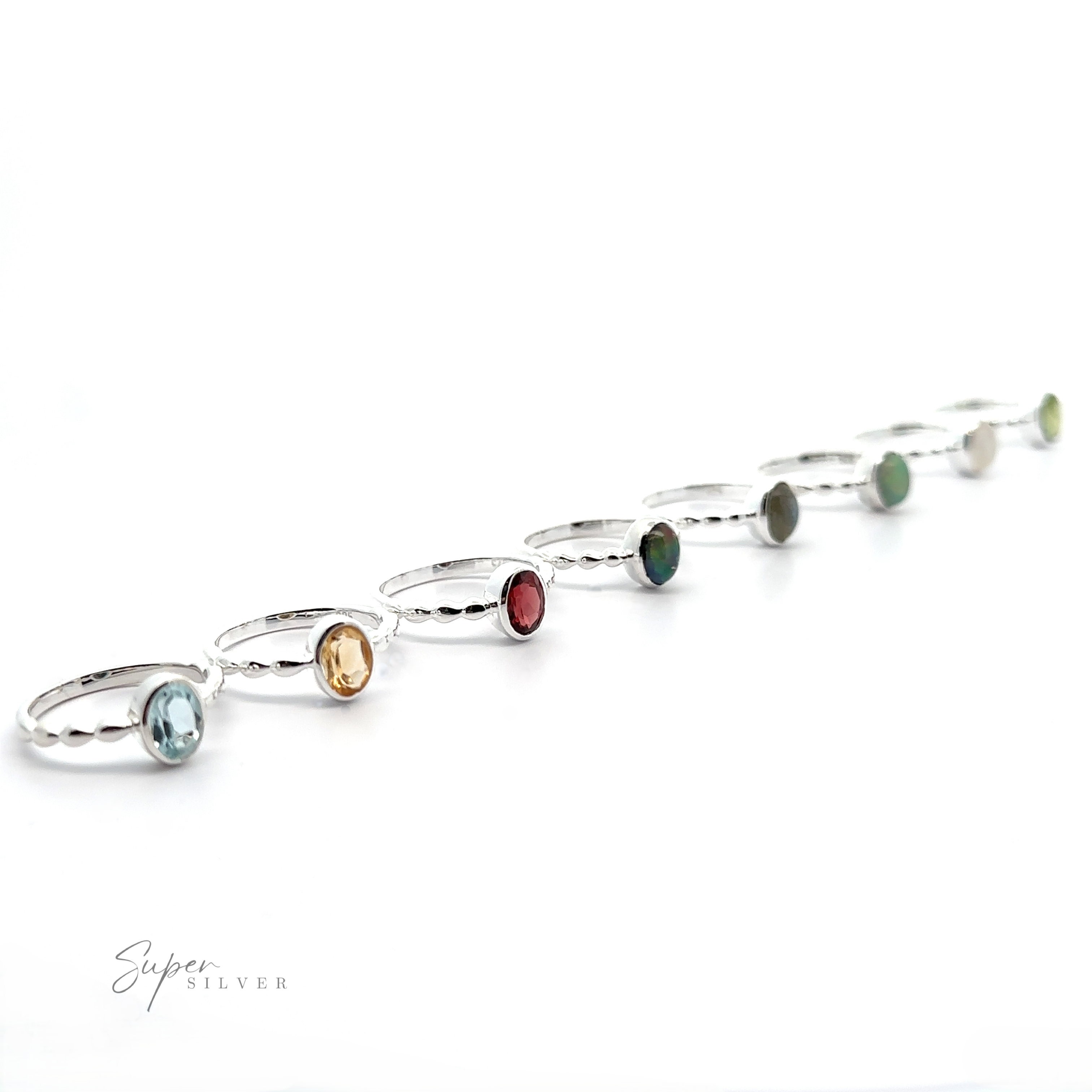A curved line of Oval Gemstone Rings with Beaded Bands, each featuring differently colored gemstones on a white background.