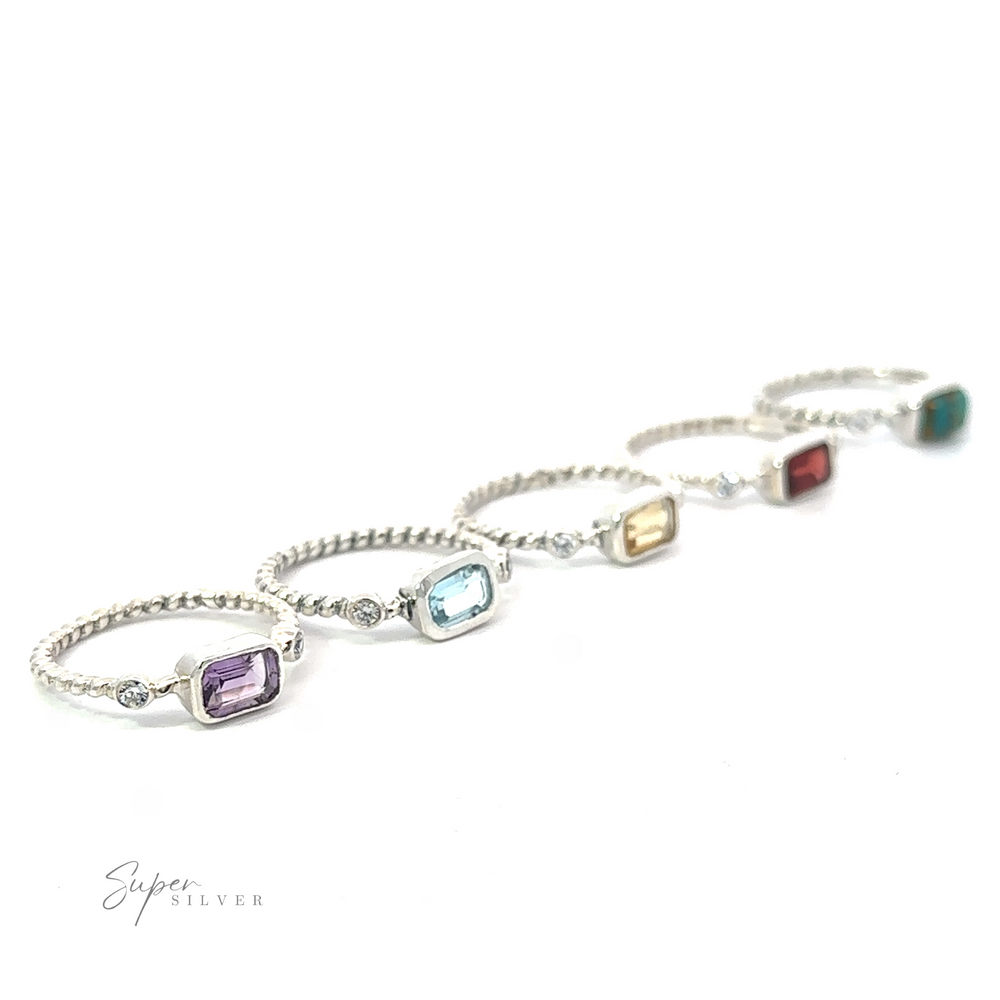 
                  
                    A line of five silver bracelets, each featuring a Rectangle Gemstone Ring with Twisted Band, sparkling with sophistication against a white background.
                  
                