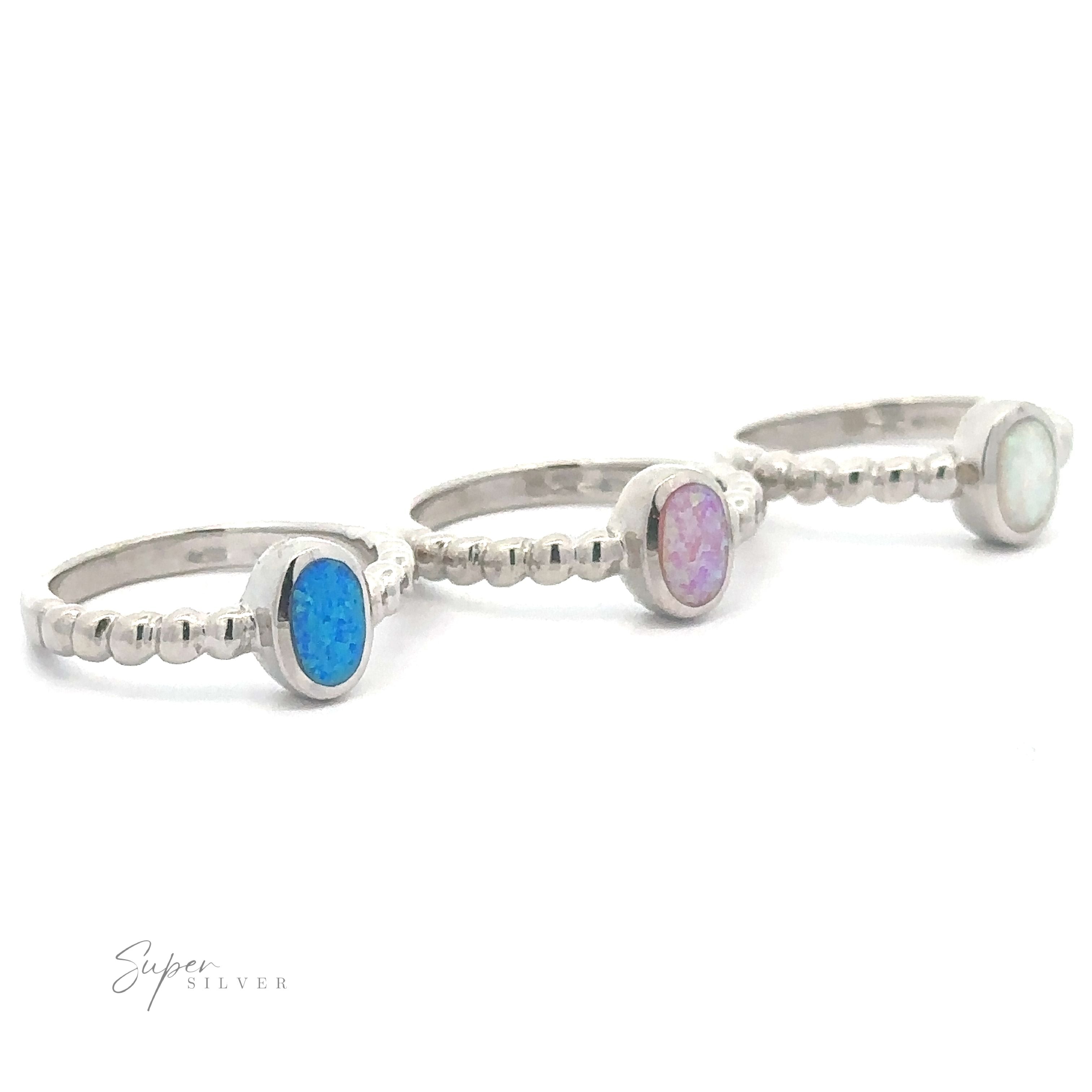 Three silver rings with Oval Lab Opal gemstones on a white background.