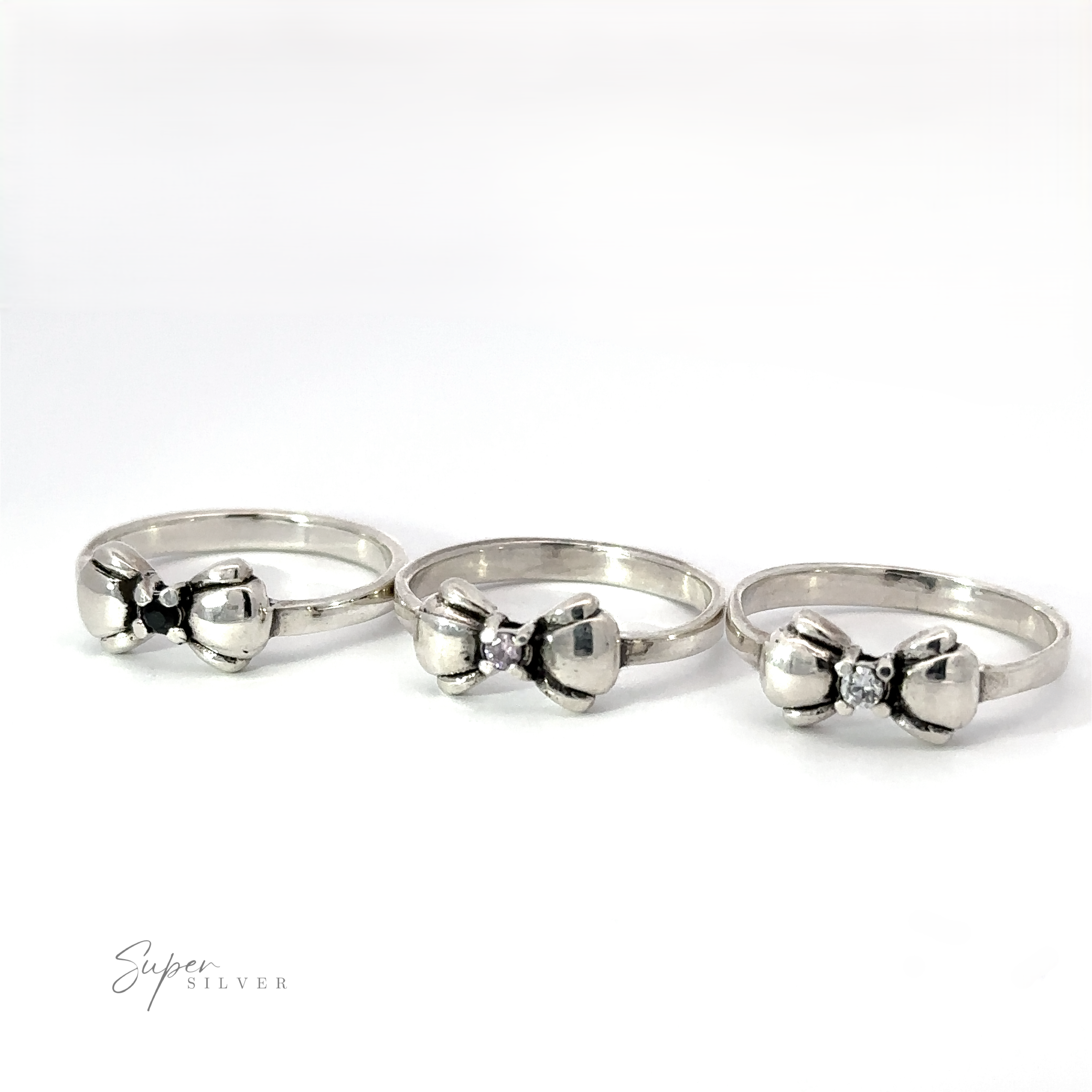 Three Adorable Cubic Zirconia Bow Rings with elegant designs are displayed in a row on a plain background. The middle bow ring appears slightly larger. The text "Super Silver" is in the lower left corner.